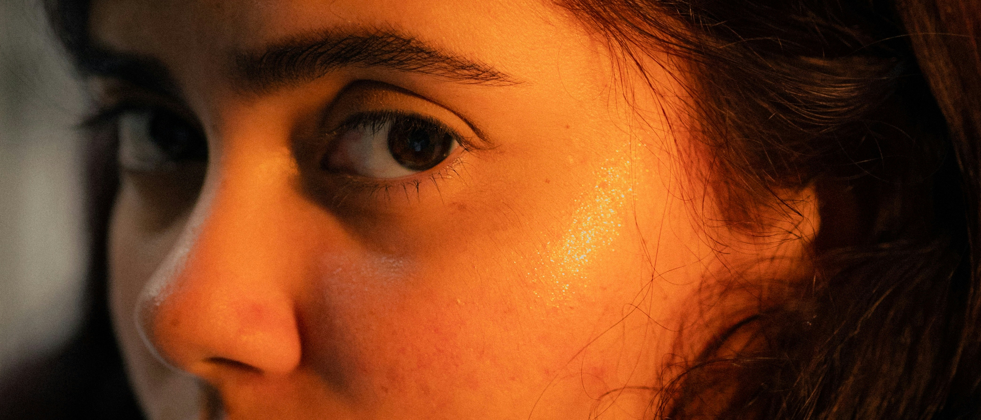 Close-up of a young woman's face with warm lighting.