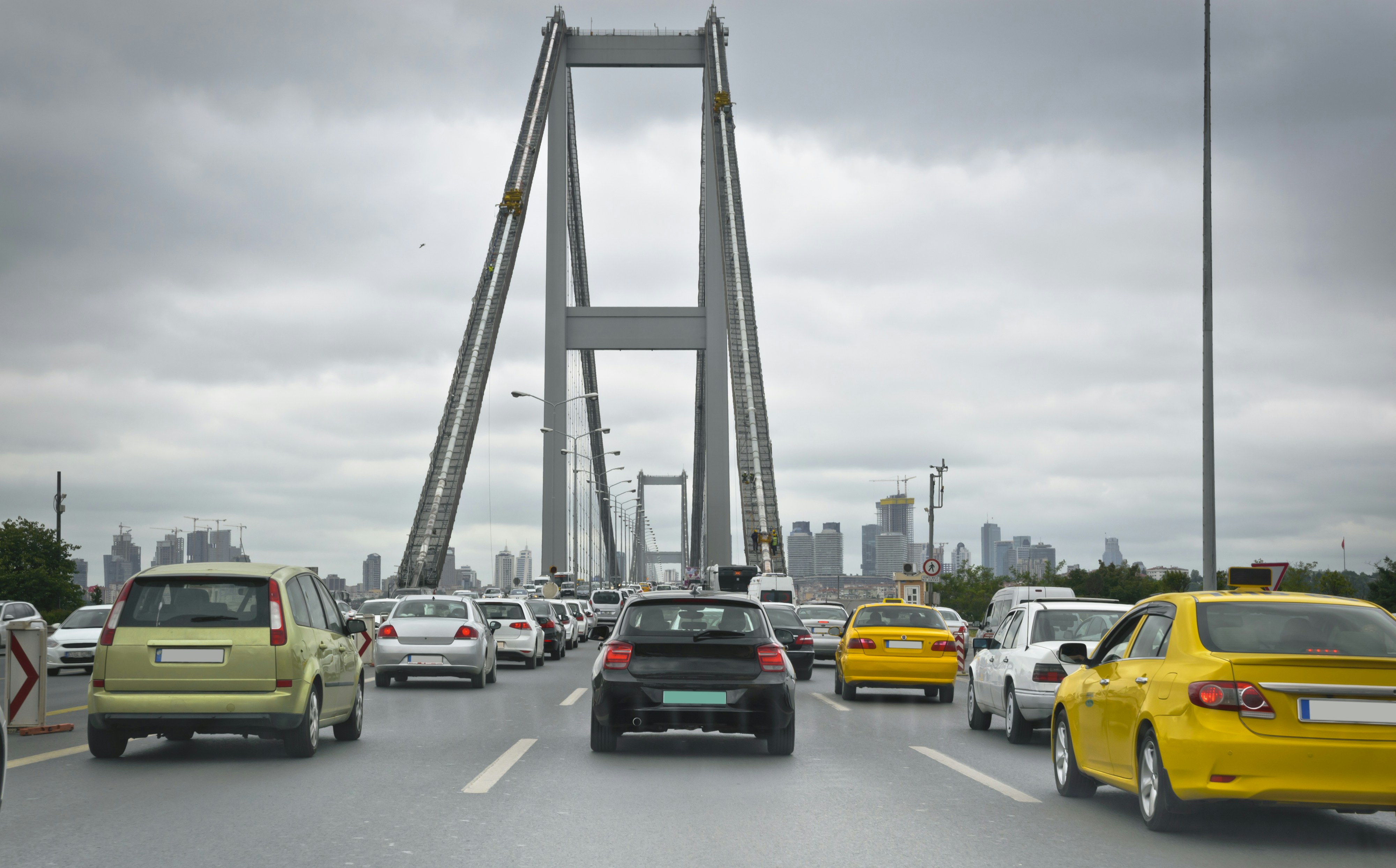 Cars driving on a bridge with city skyline.