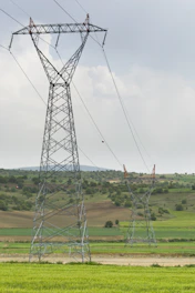 Two tall power line towers in a green field.
