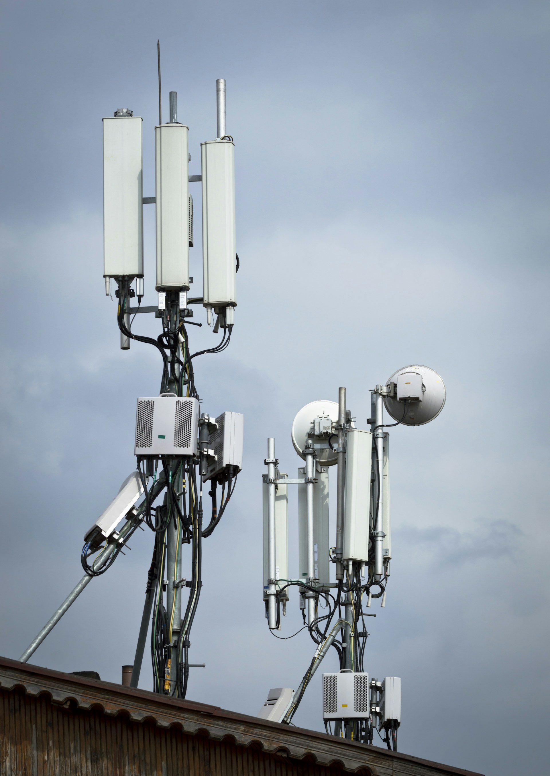 Cell towers with antennas against a cloudy sky