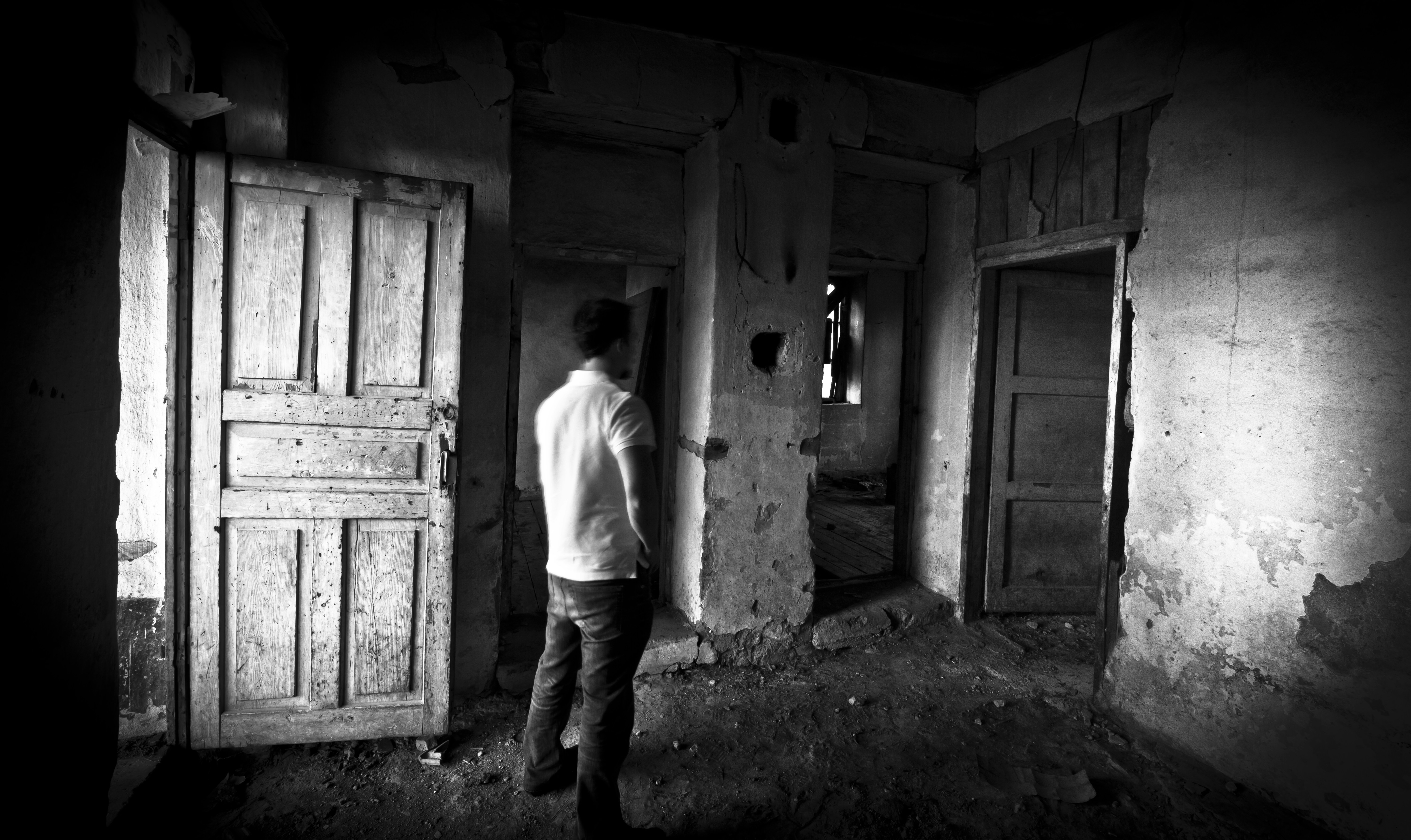 Man stands in a dark, dilapidated room.