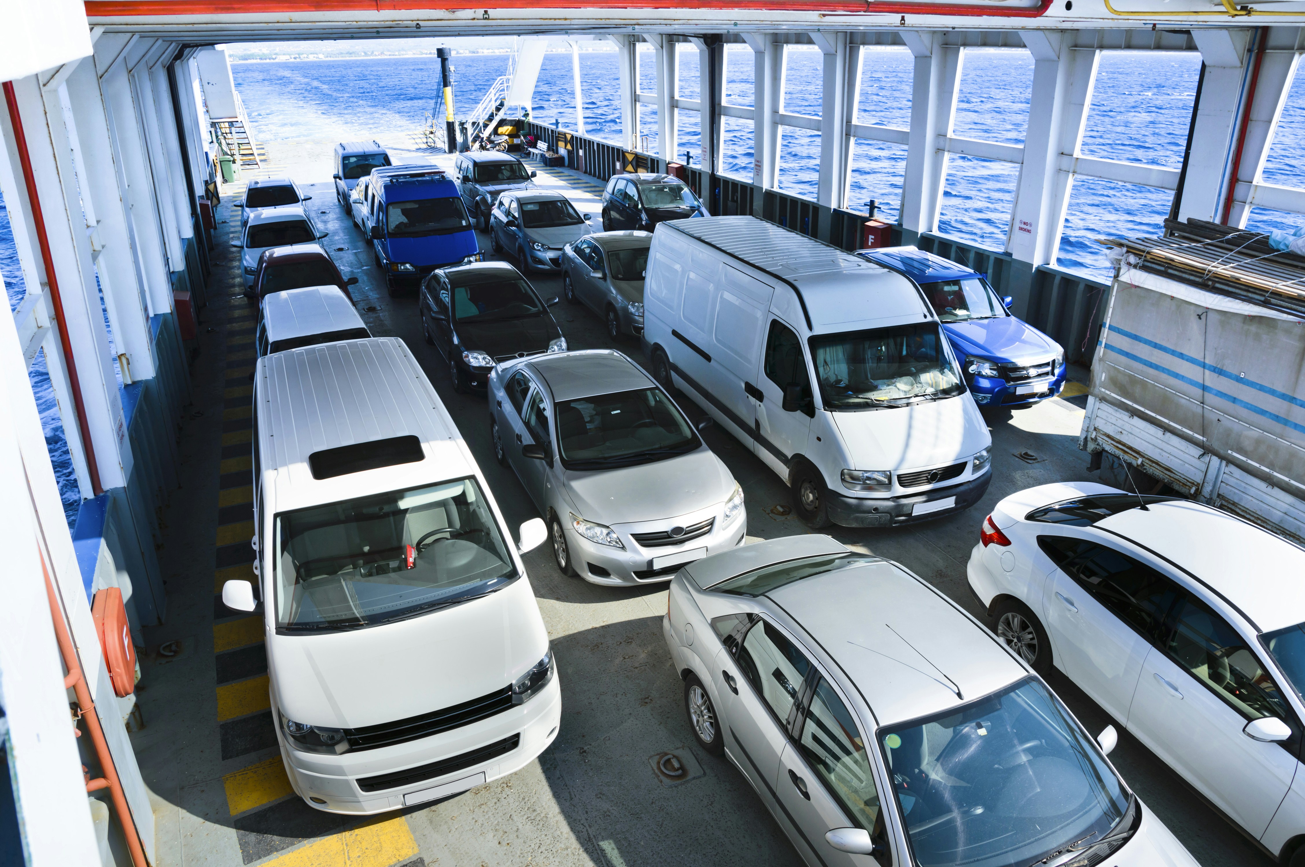 Cars lined up on a ferry crossing the ocean.