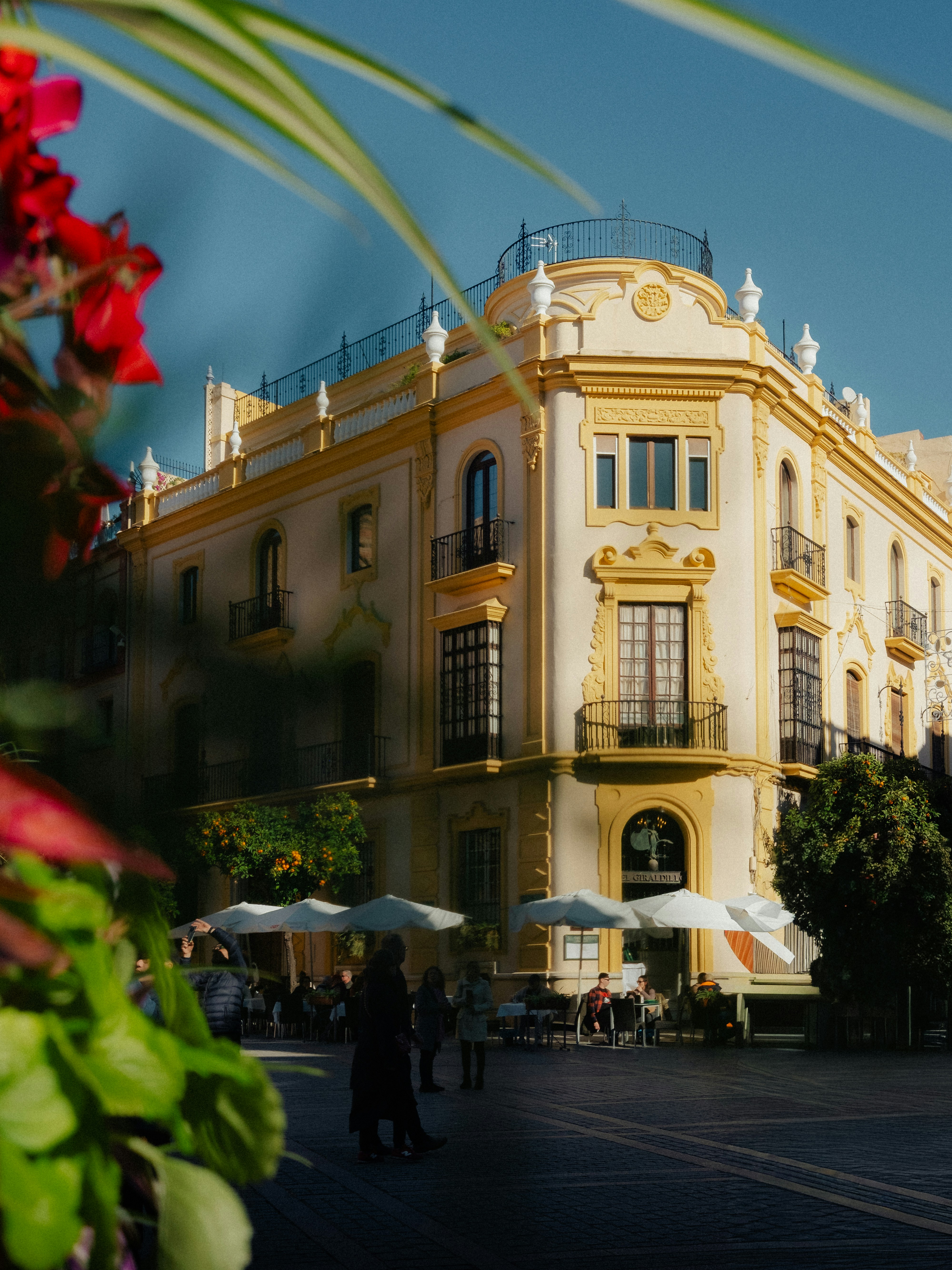 Ornate building with outdoor cafe seating in sunlight.
