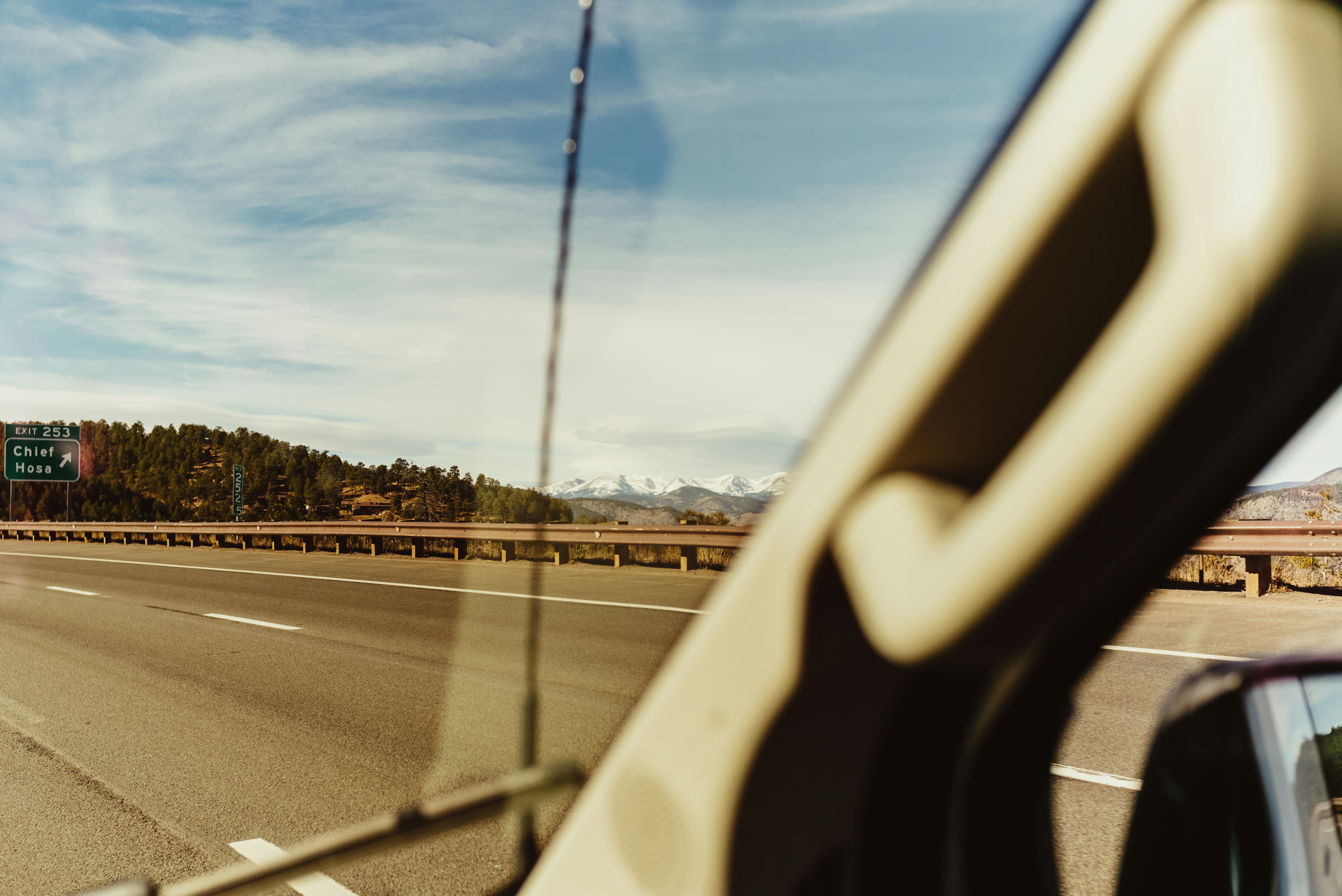 Driving down a highway with trees and mountains.