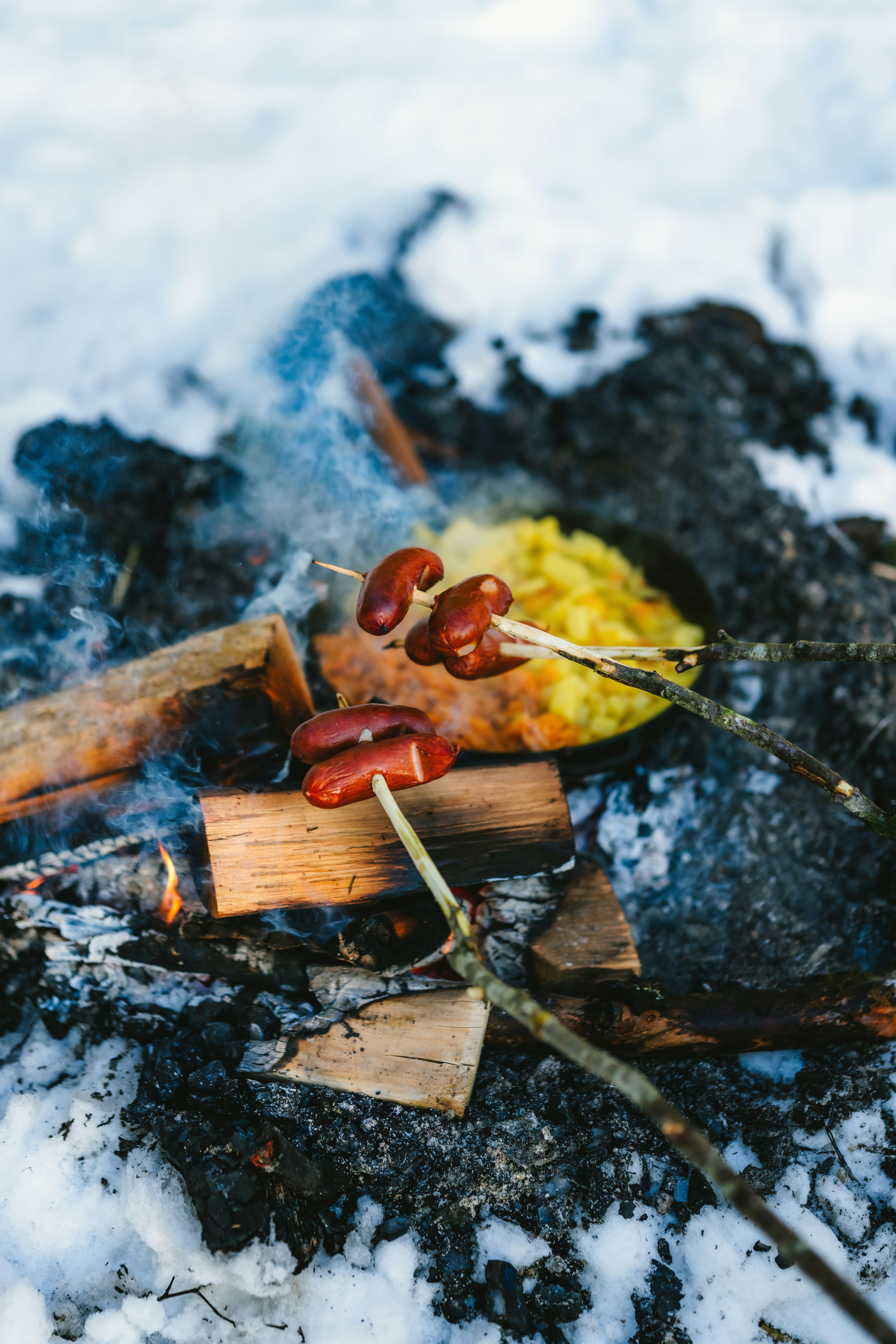 Sausages cooking over a campfire in the snow