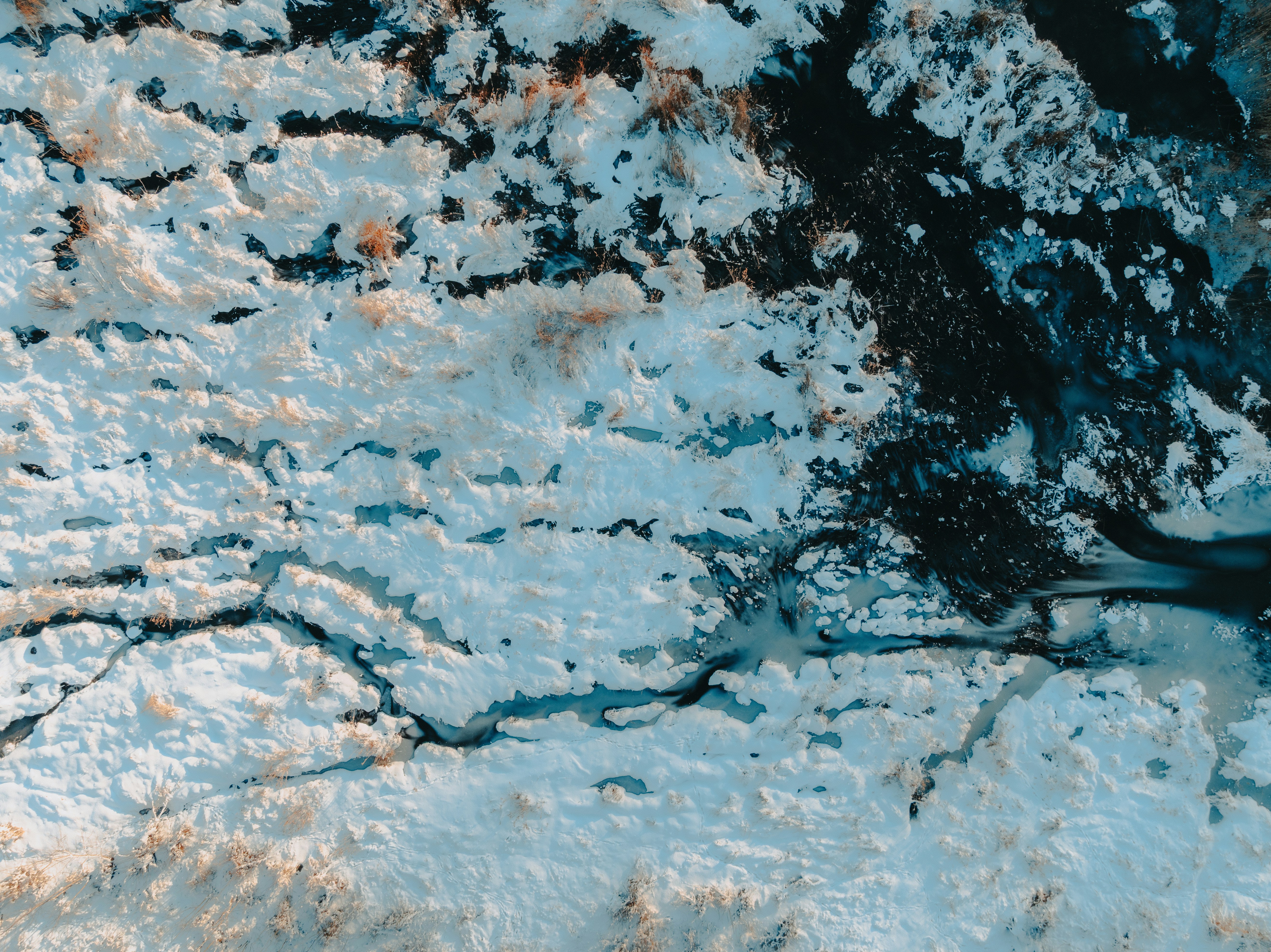 Snowy landscape with frozen river from above