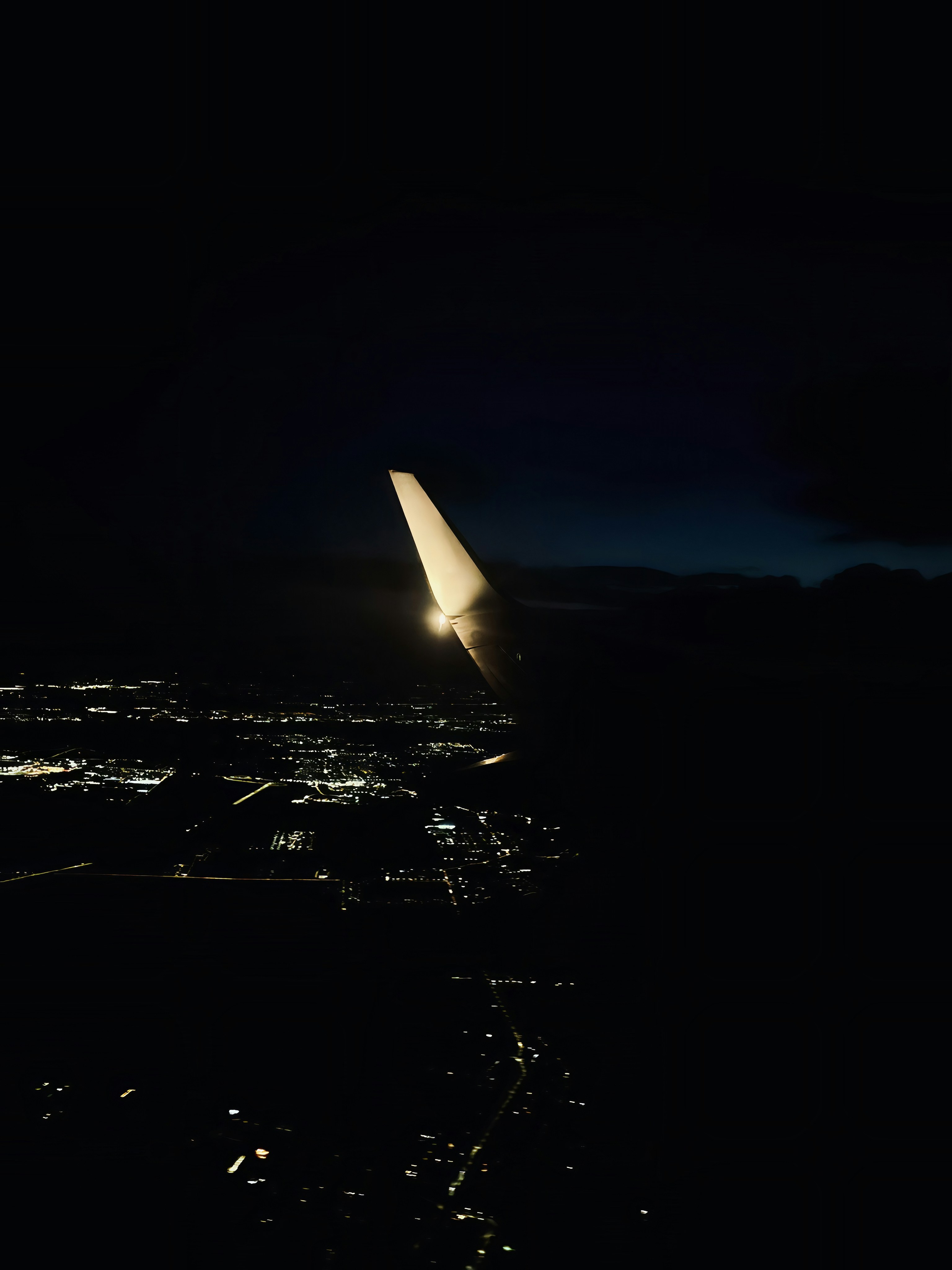 夜の街灯の上空を飛行機の翼