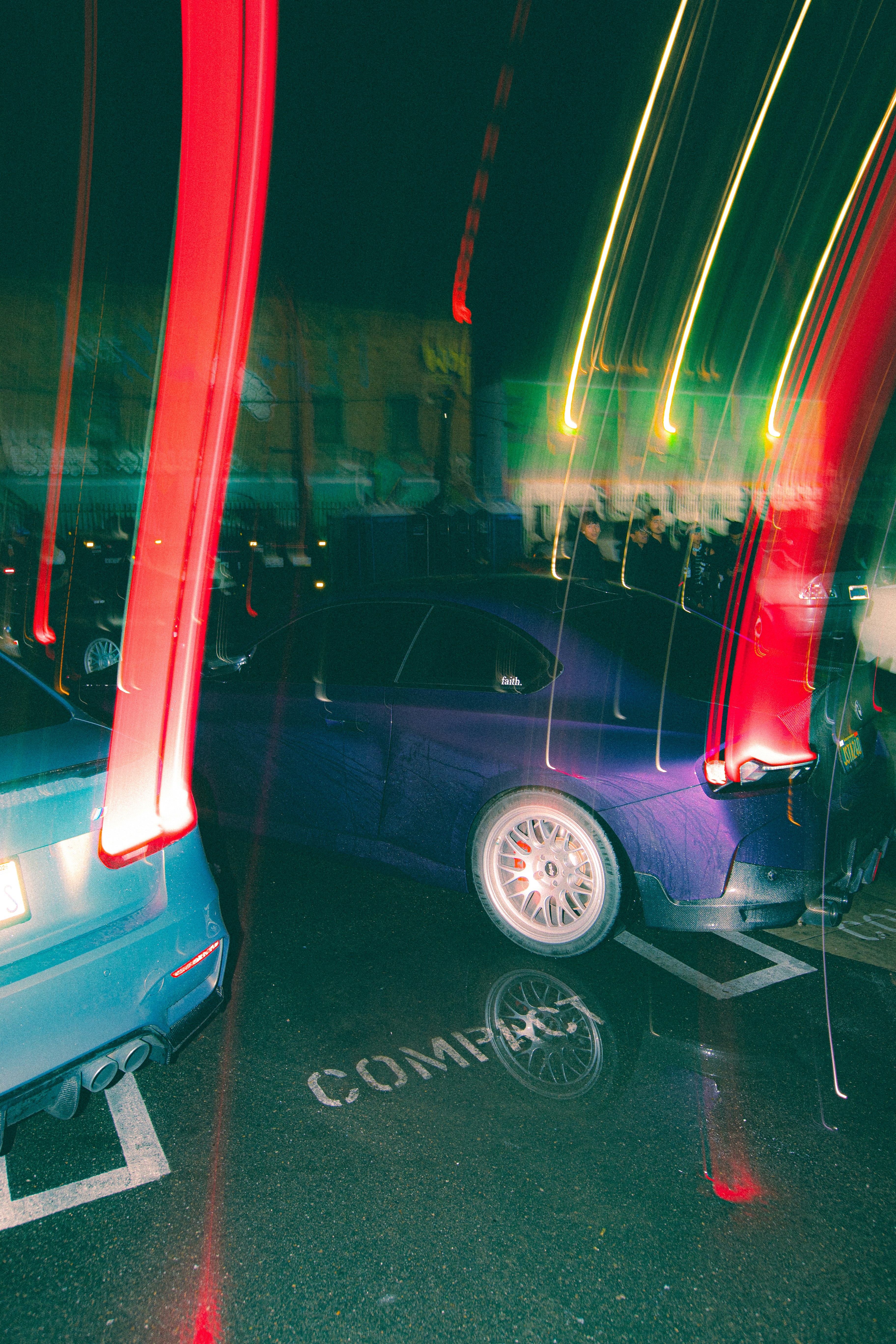Blurry streaks of red and yellow light over parked cars.