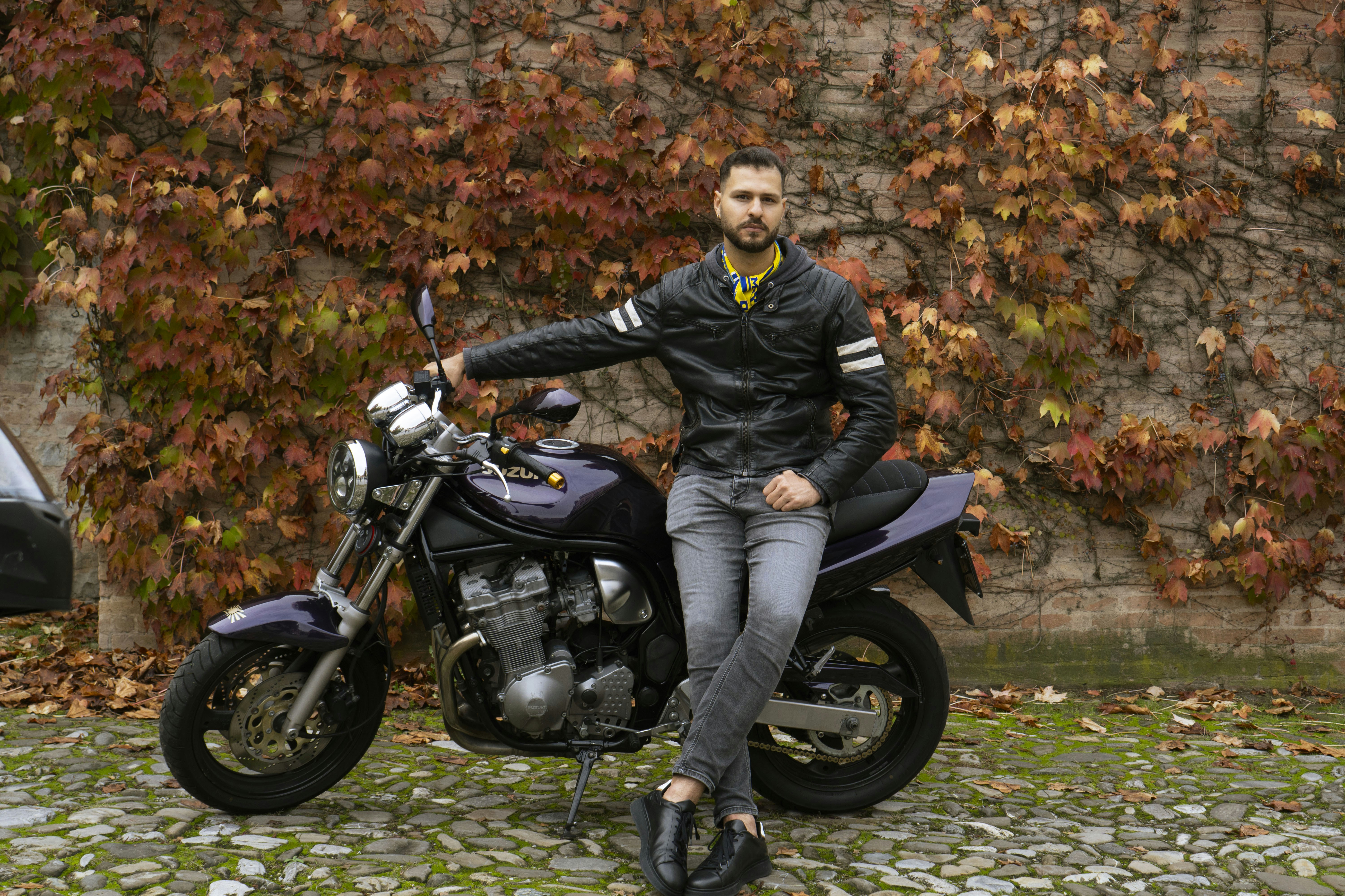 Man in leather jacket with motorcycle and autumn leaves