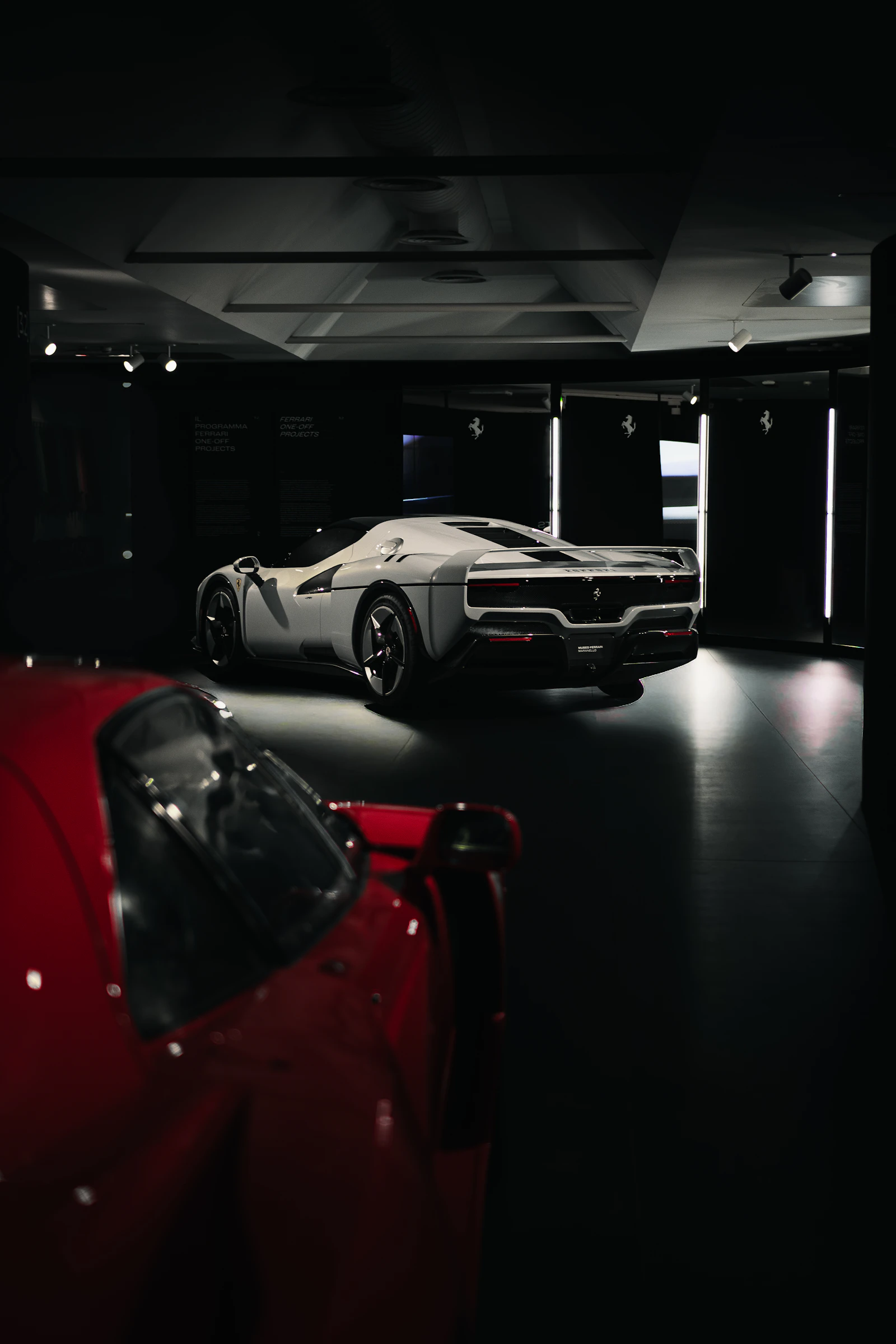 Two luxury sports cars displayed in a dark showroom