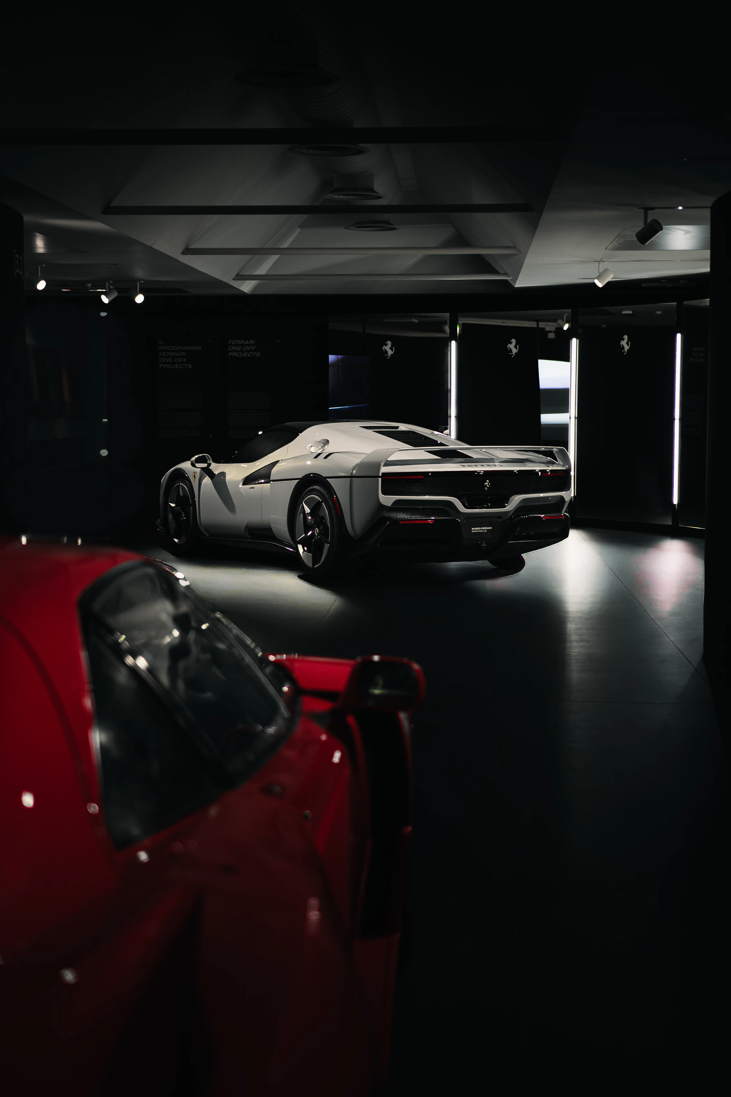 Two luxury sports cars displayed in a dark showroom
