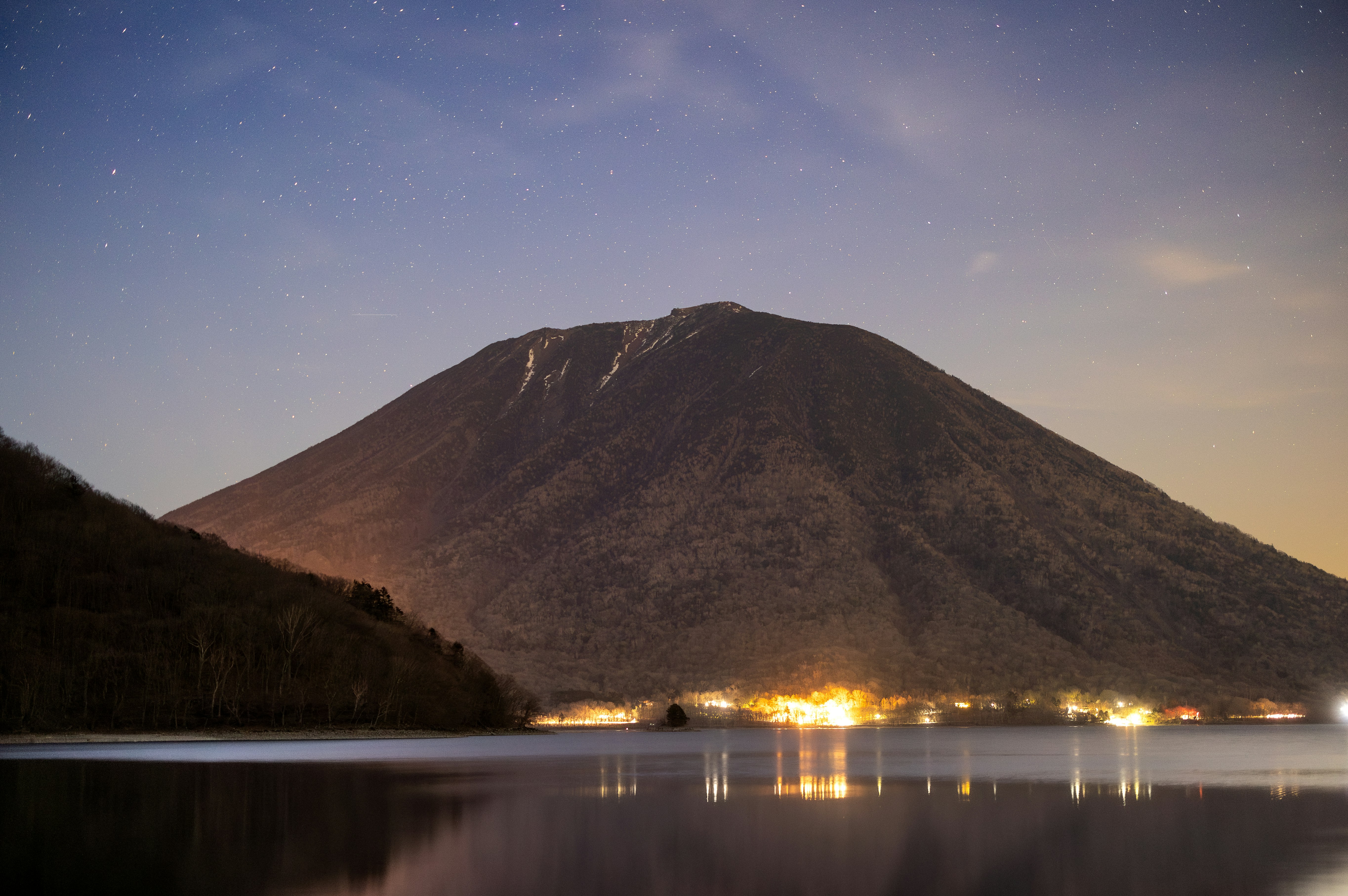 A mountain looms over a town at night.