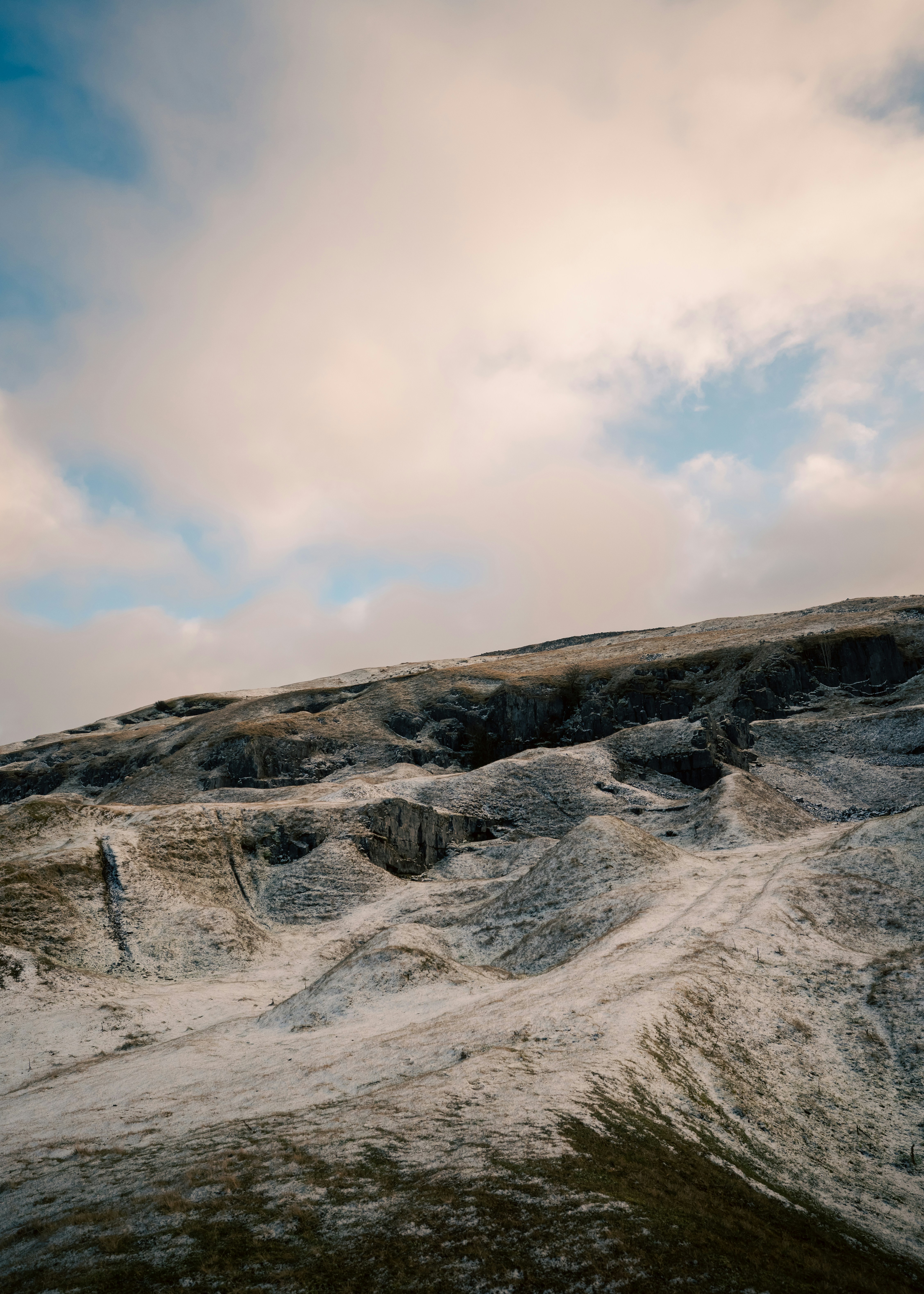 Snow-dusted hills under a cloudy sky