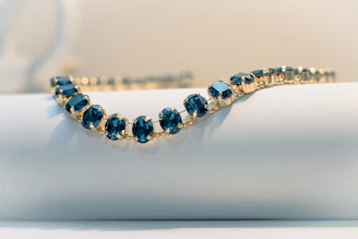A delicate gold bracelet with dark blue gems.