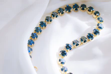 Gold necklace with oval blue gemstones on white silk