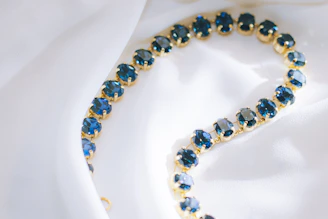 Gold necklace with oval blue gemstones on white silk