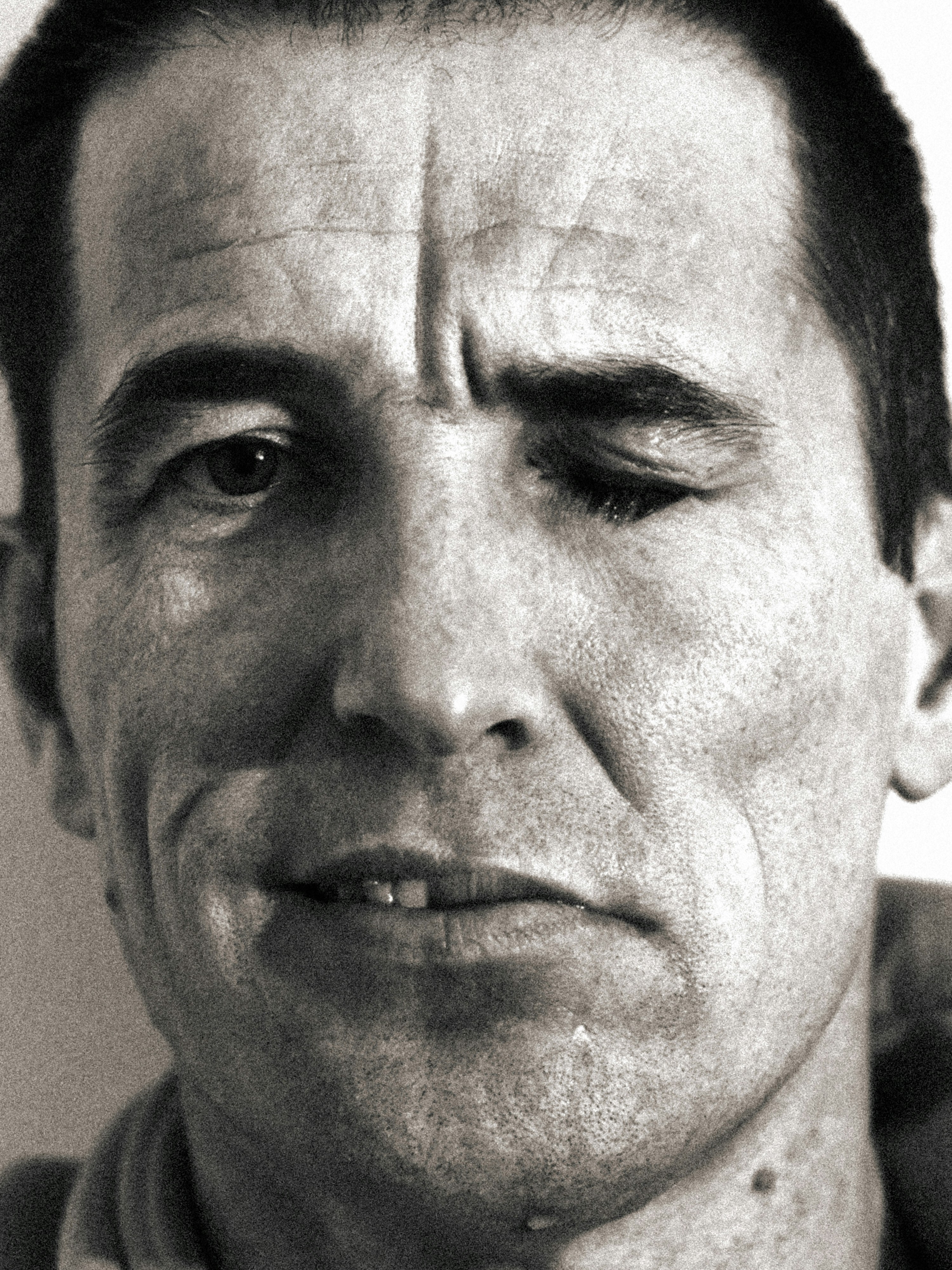 Close-up of a man's face with one eye closed.