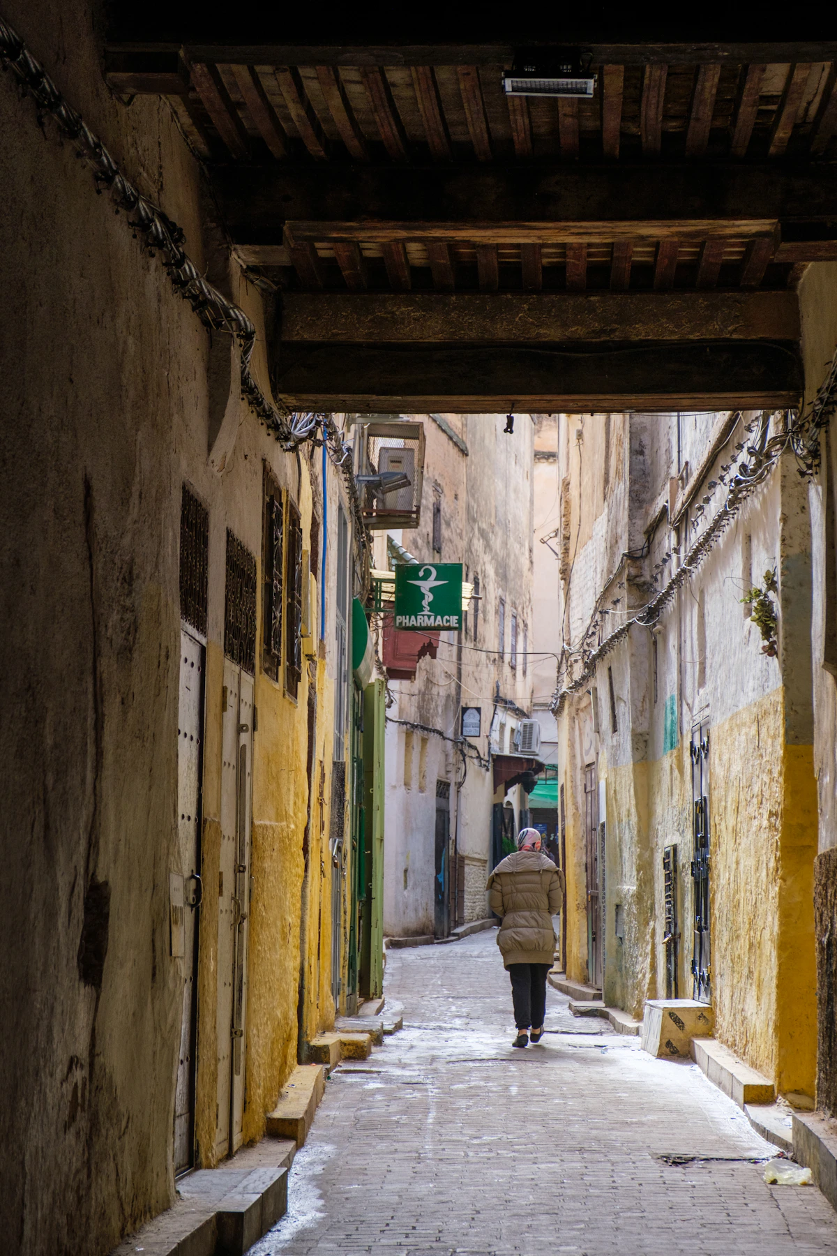 A woman walking through a narrow stone lane in the old medina of Fès
