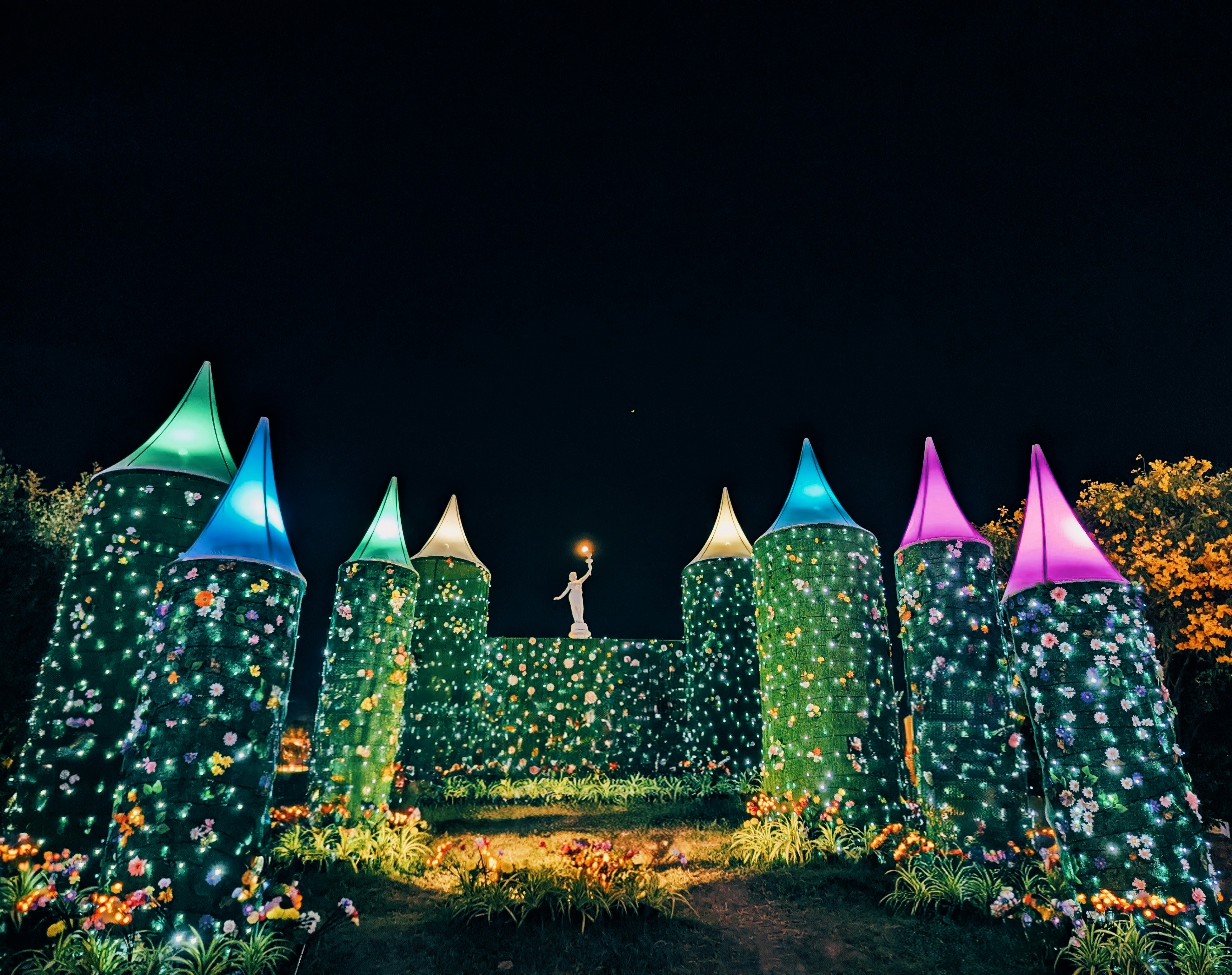 Woman standing atop a castle adorned with flowers at night