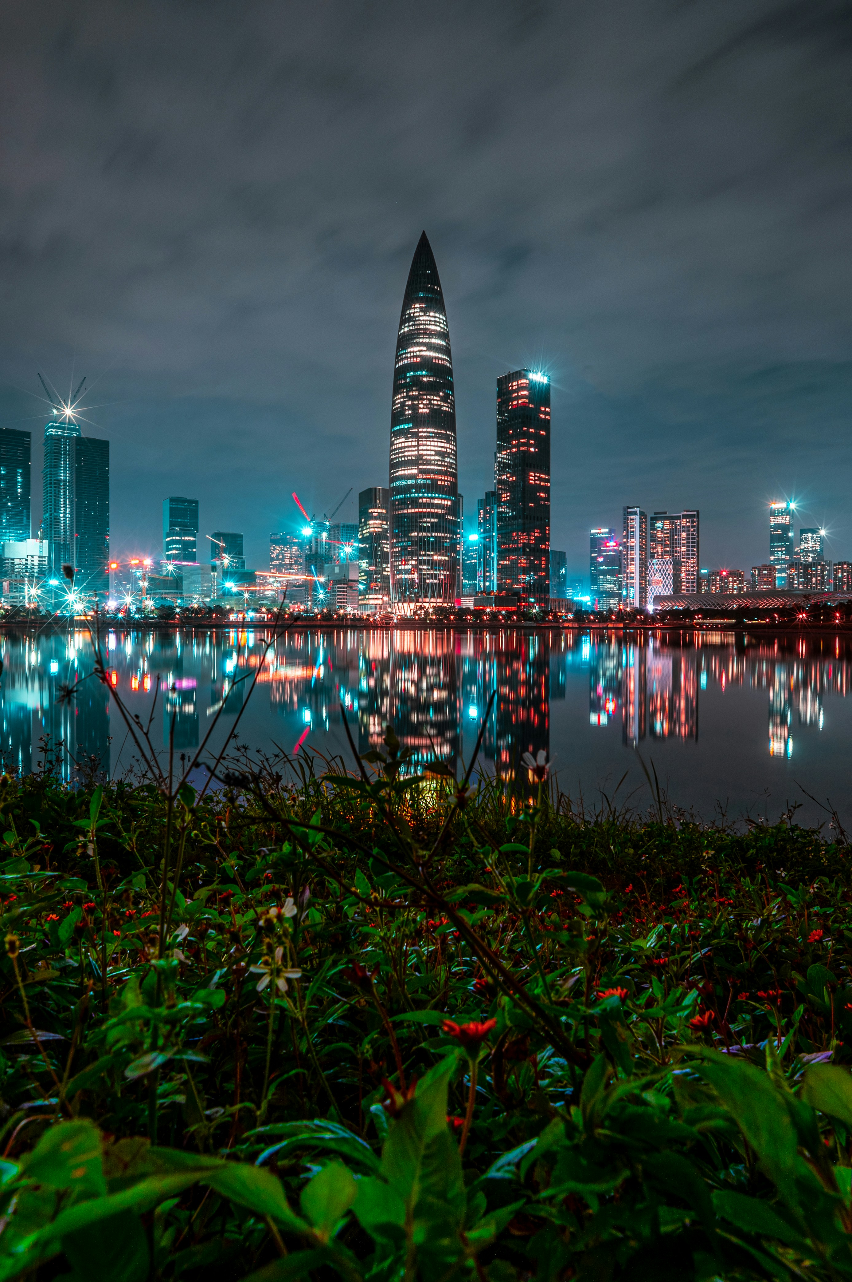 City skyline with illuminated skyscrapers reflected in water.