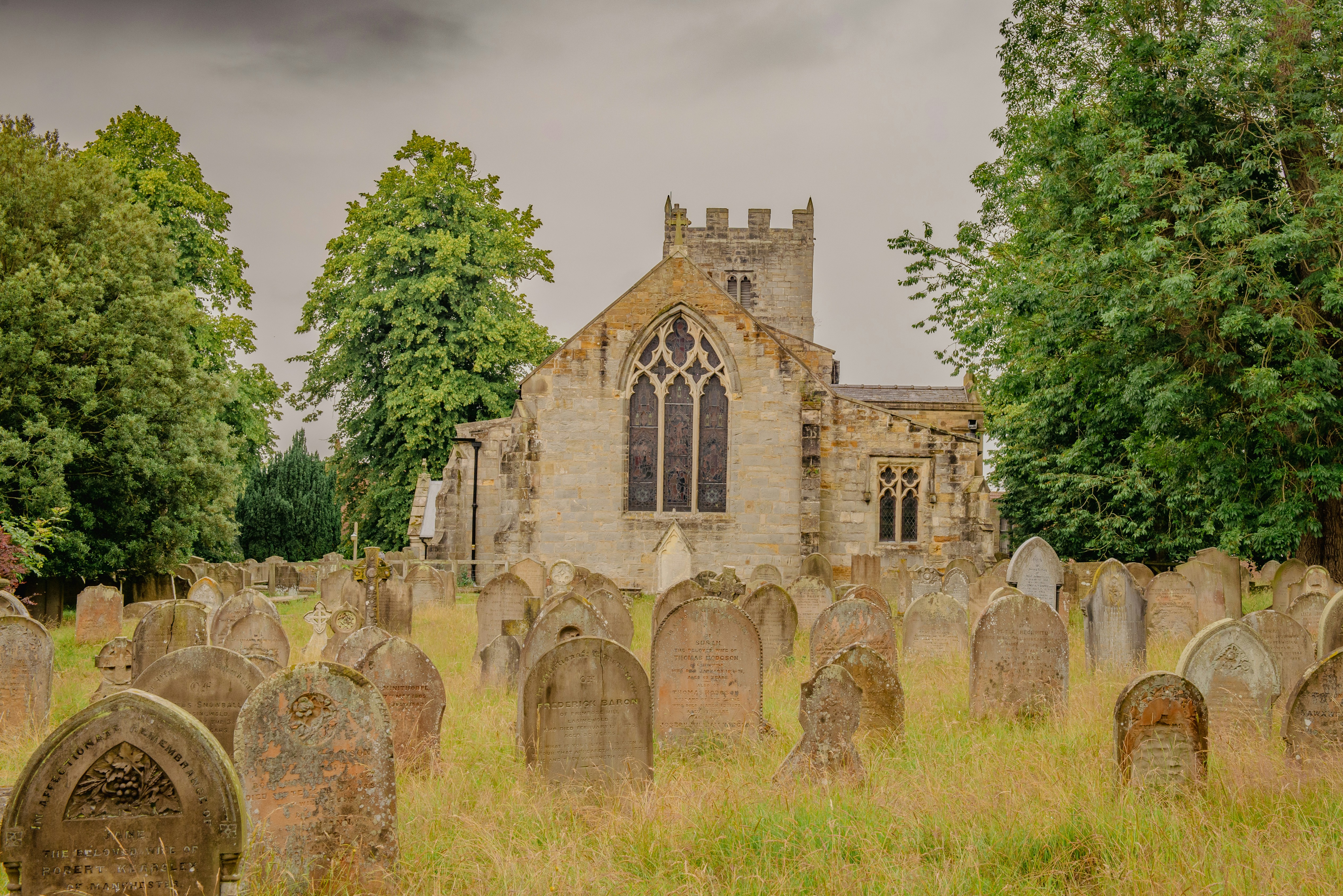 Old tombstones in a grassy graveyard near church