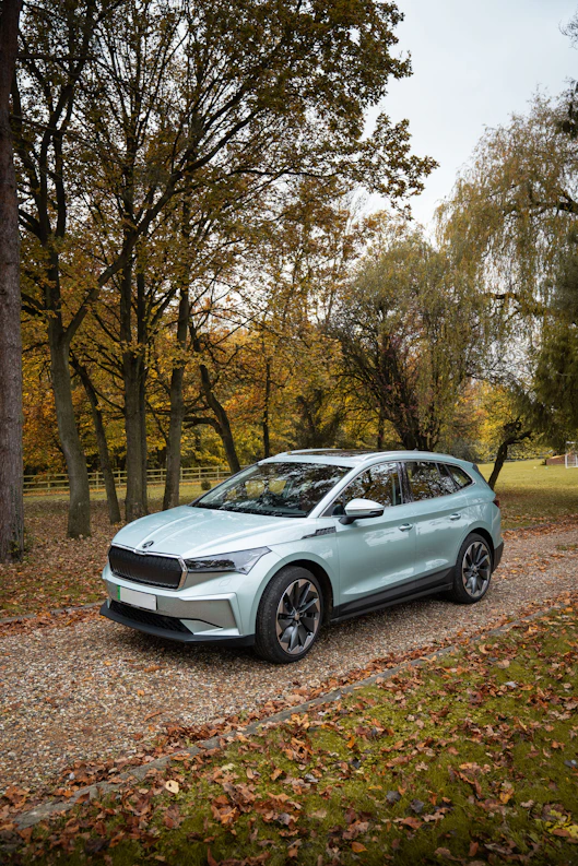 A light blue electric suv parked on a gravel road.