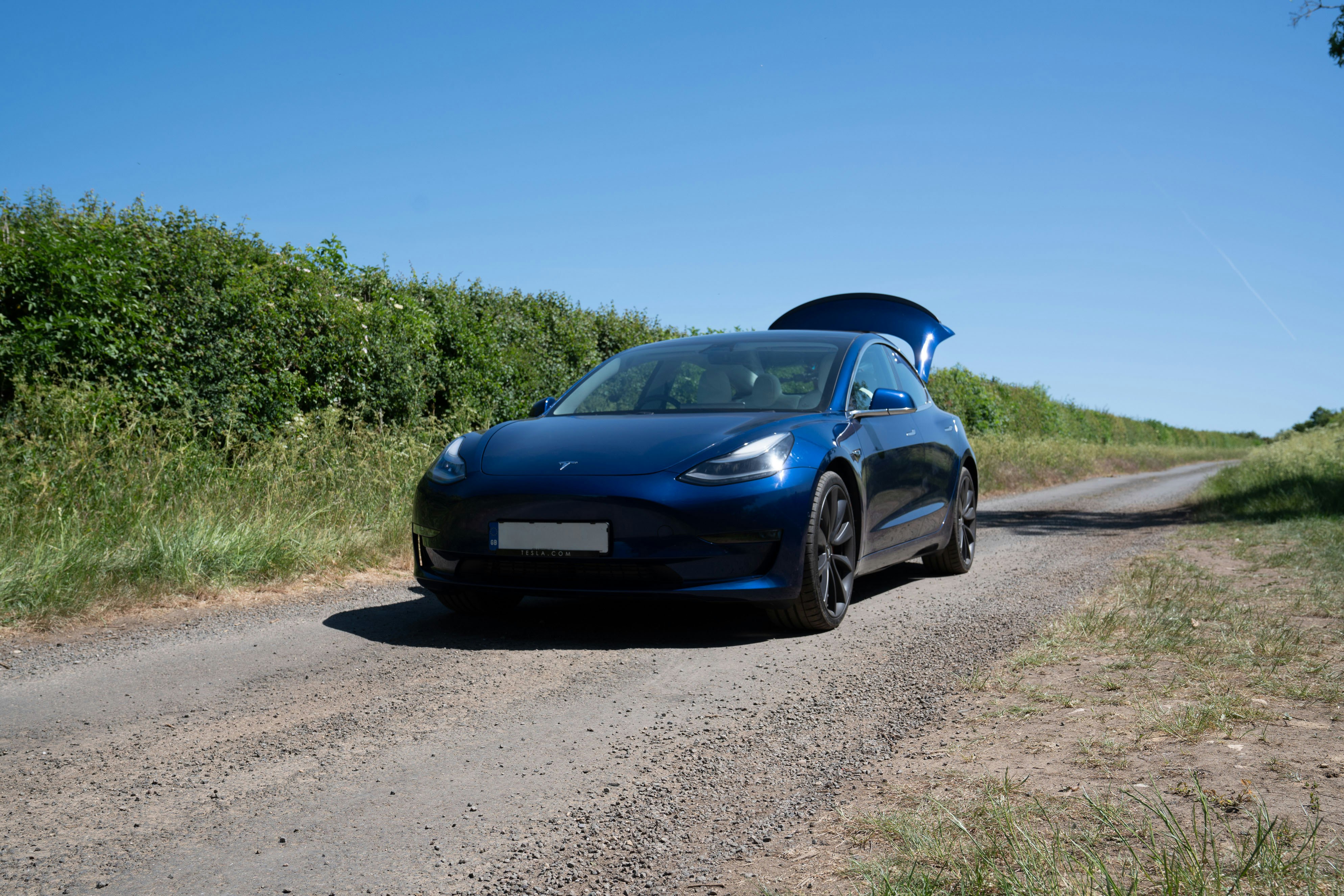Blue tesla car parked on a dirt road
