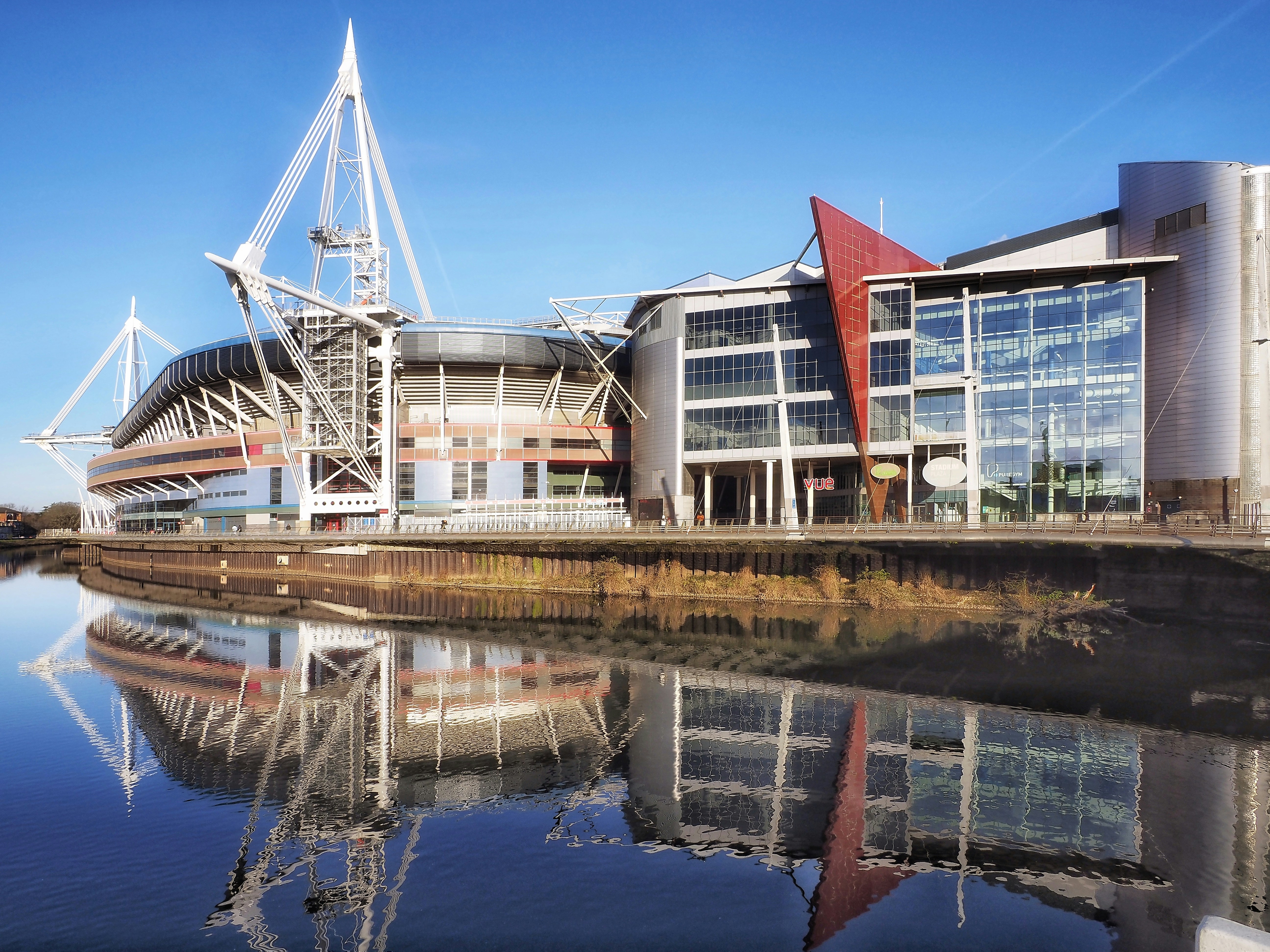 Modern stadium reflected in calm water under blue sky
