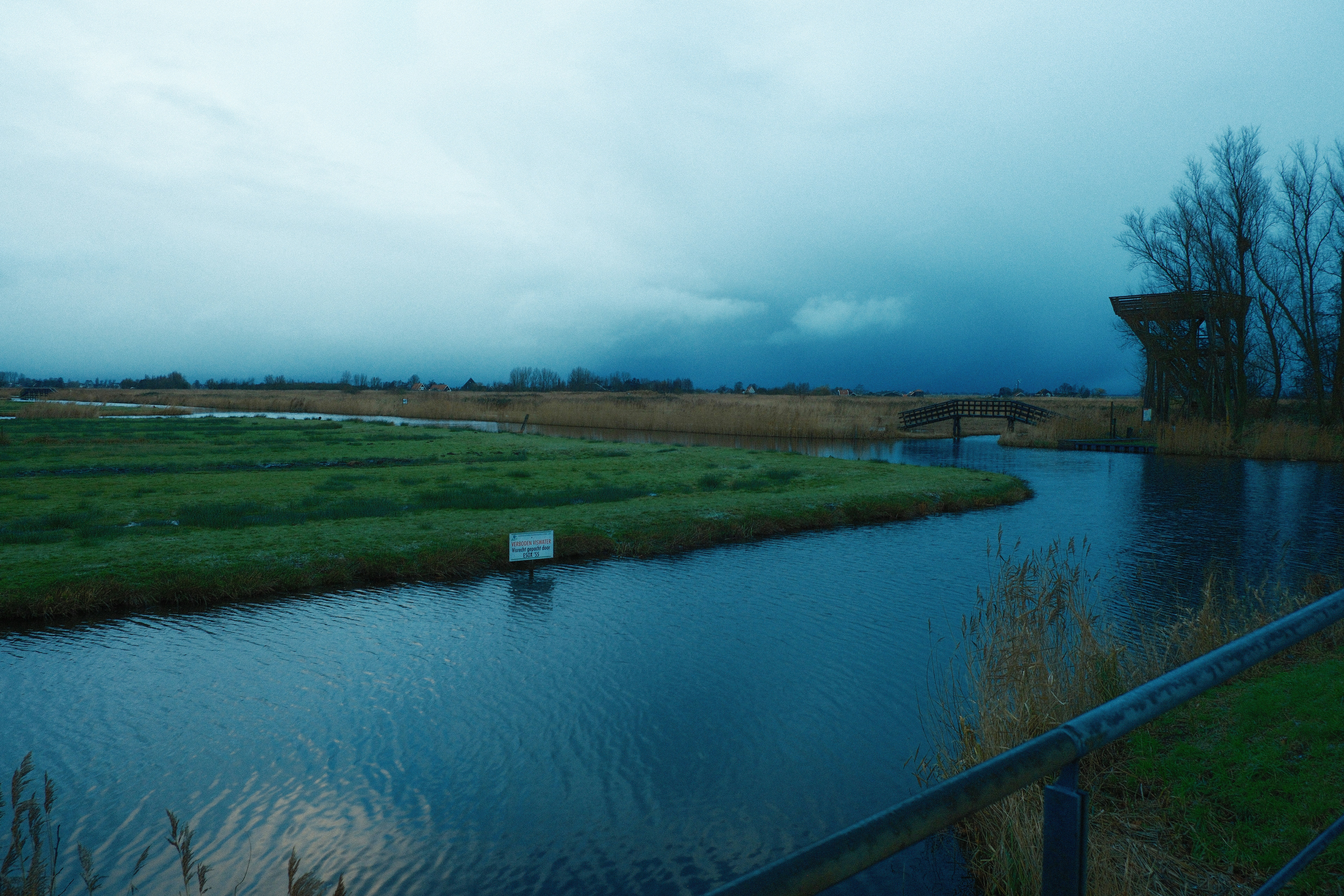 A dark, cloudy sky over a calm river and marsh.