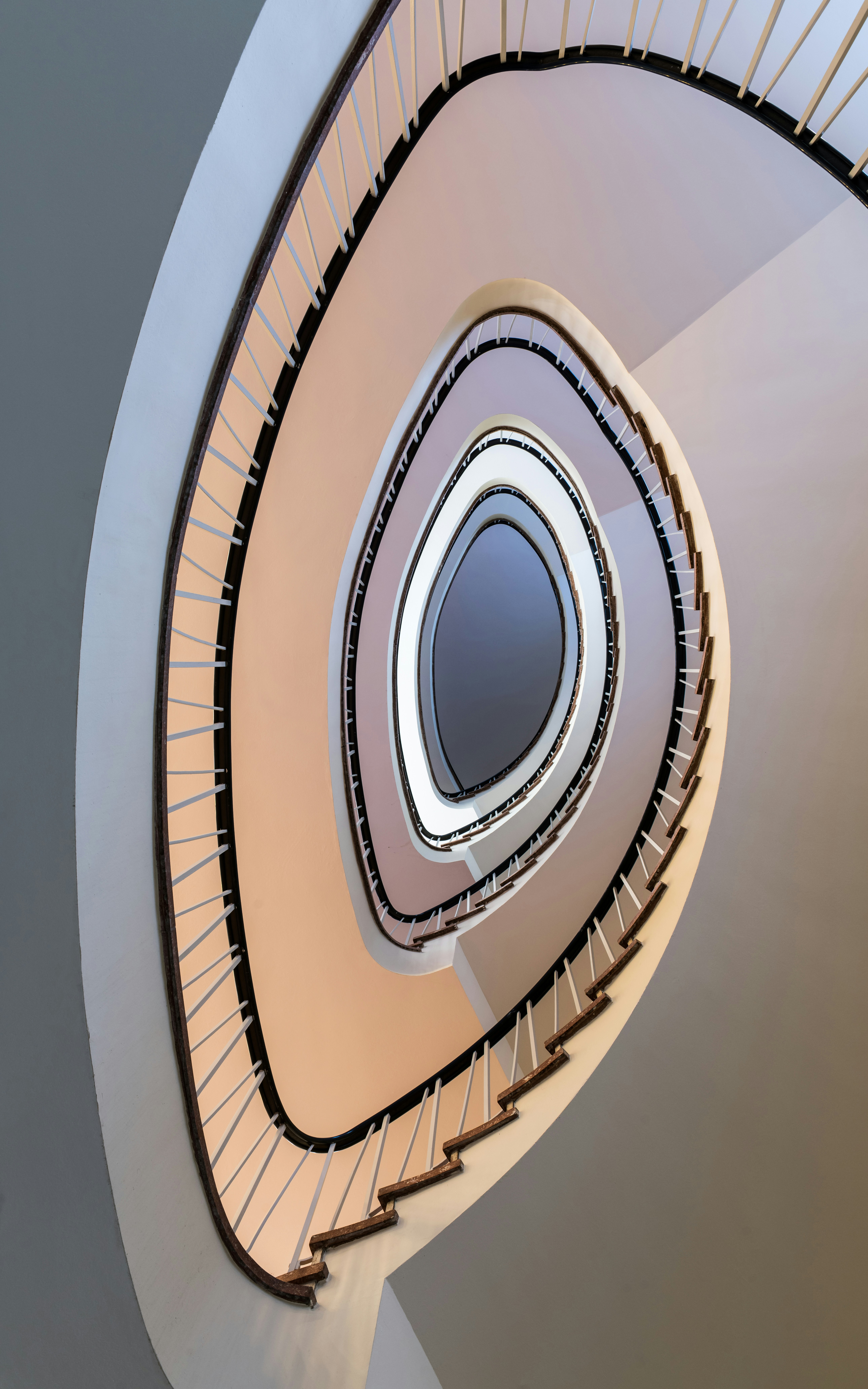 Looking down a modern spiral staircase with wooden steps.