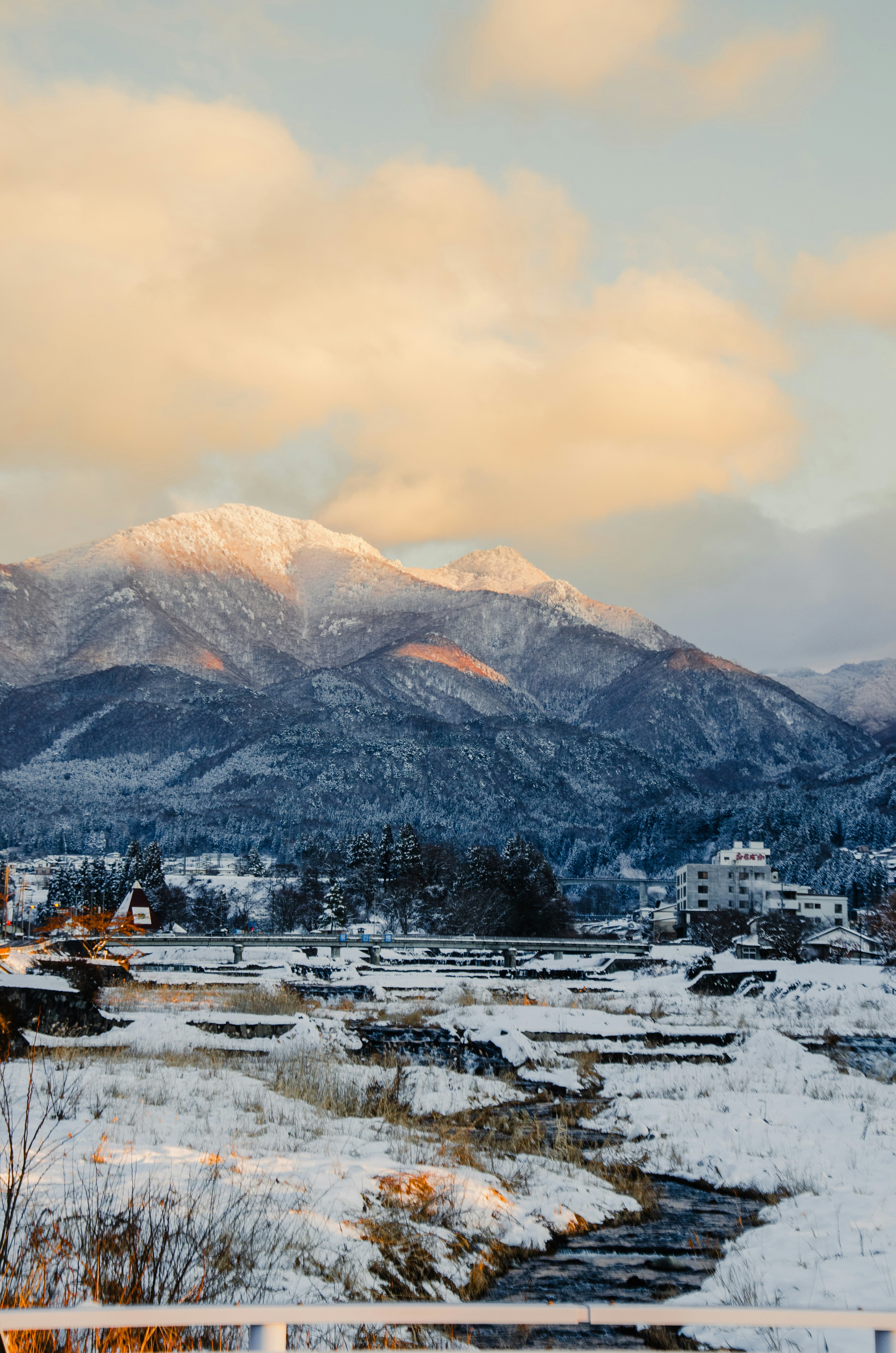 Snow-covered mountains at sunrise with a village below.