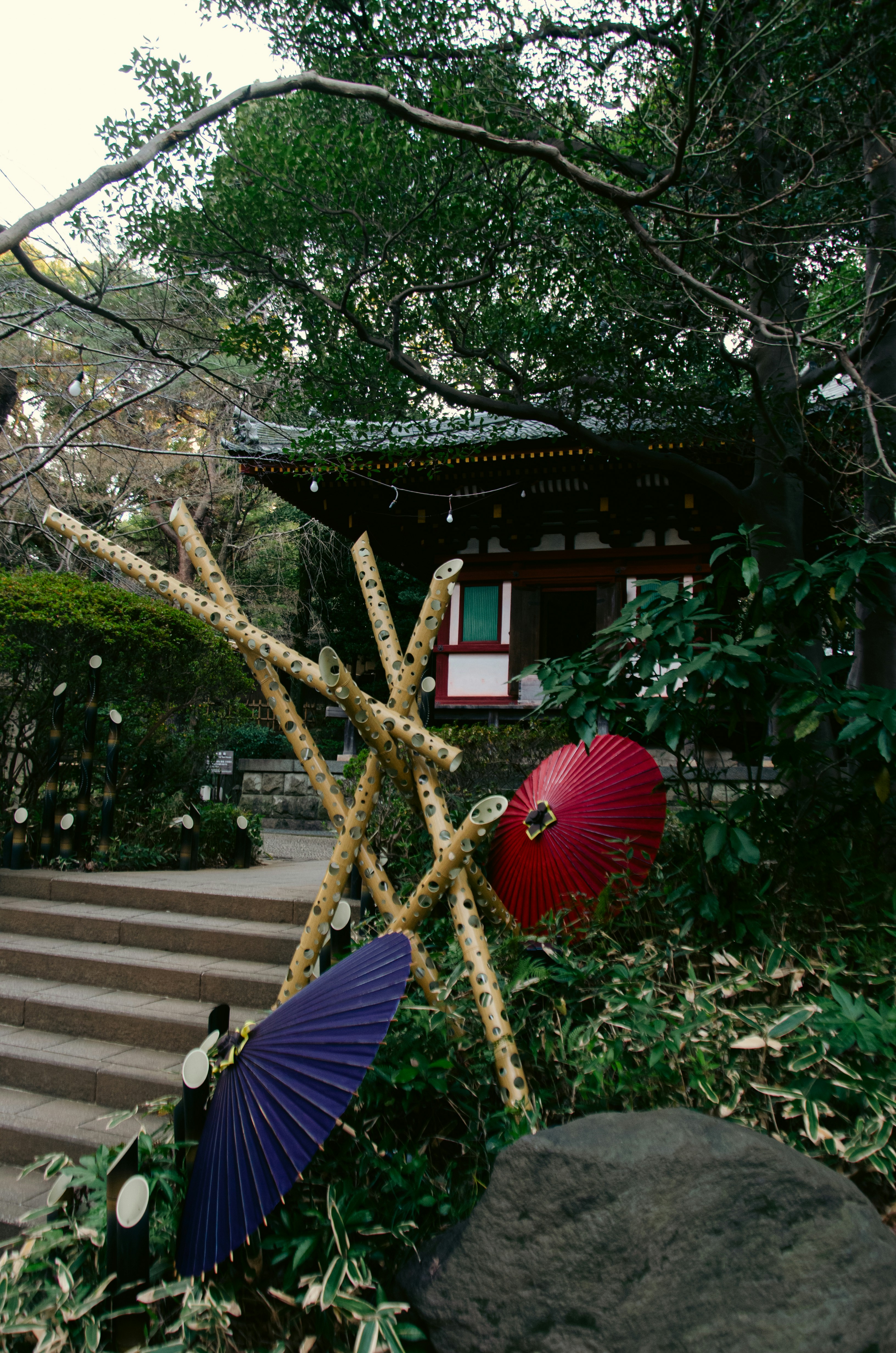 Red and purple umbrellas near a japanese shrine.