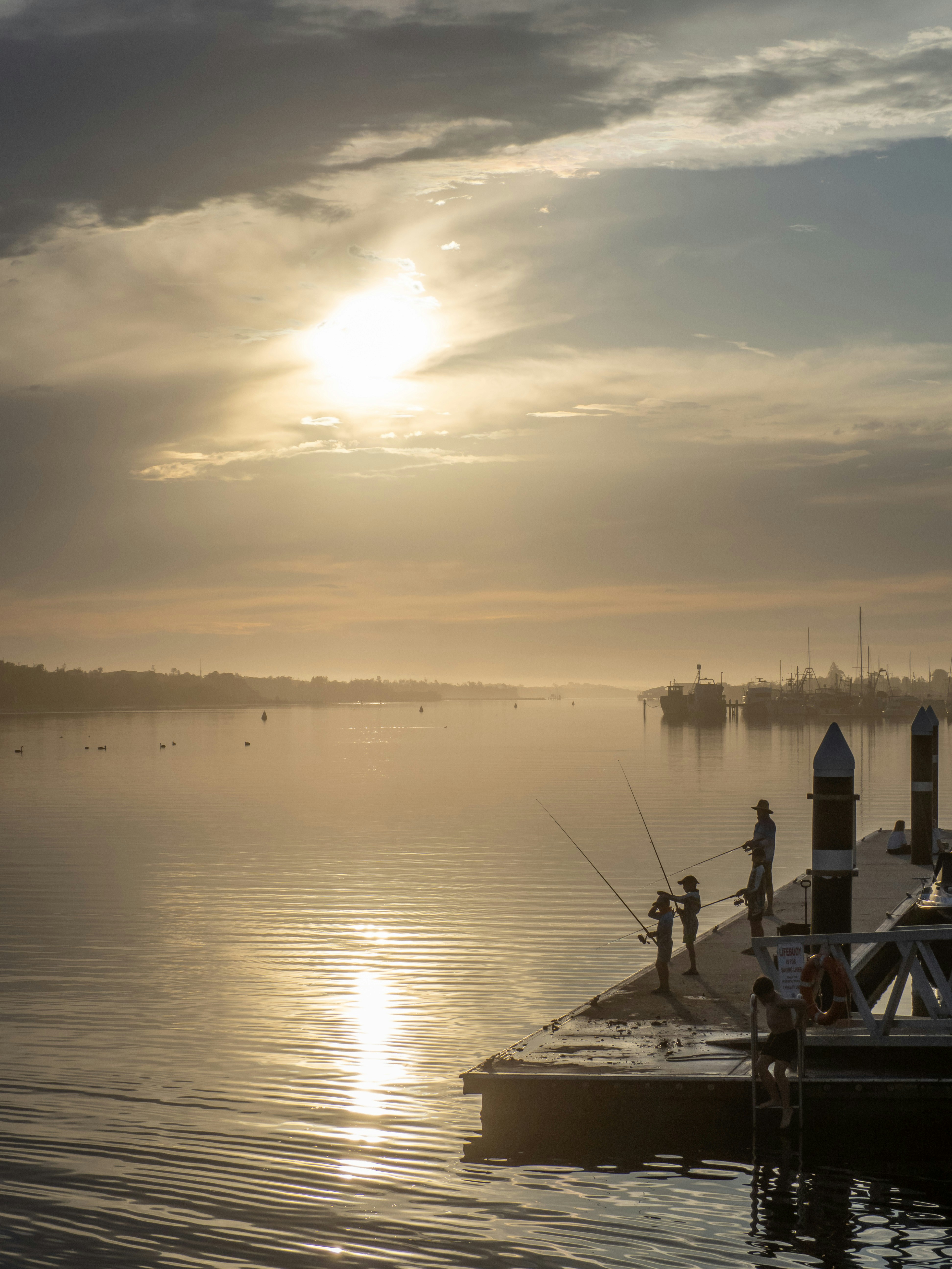 Family fishing from a dock at sunrise with golden light.