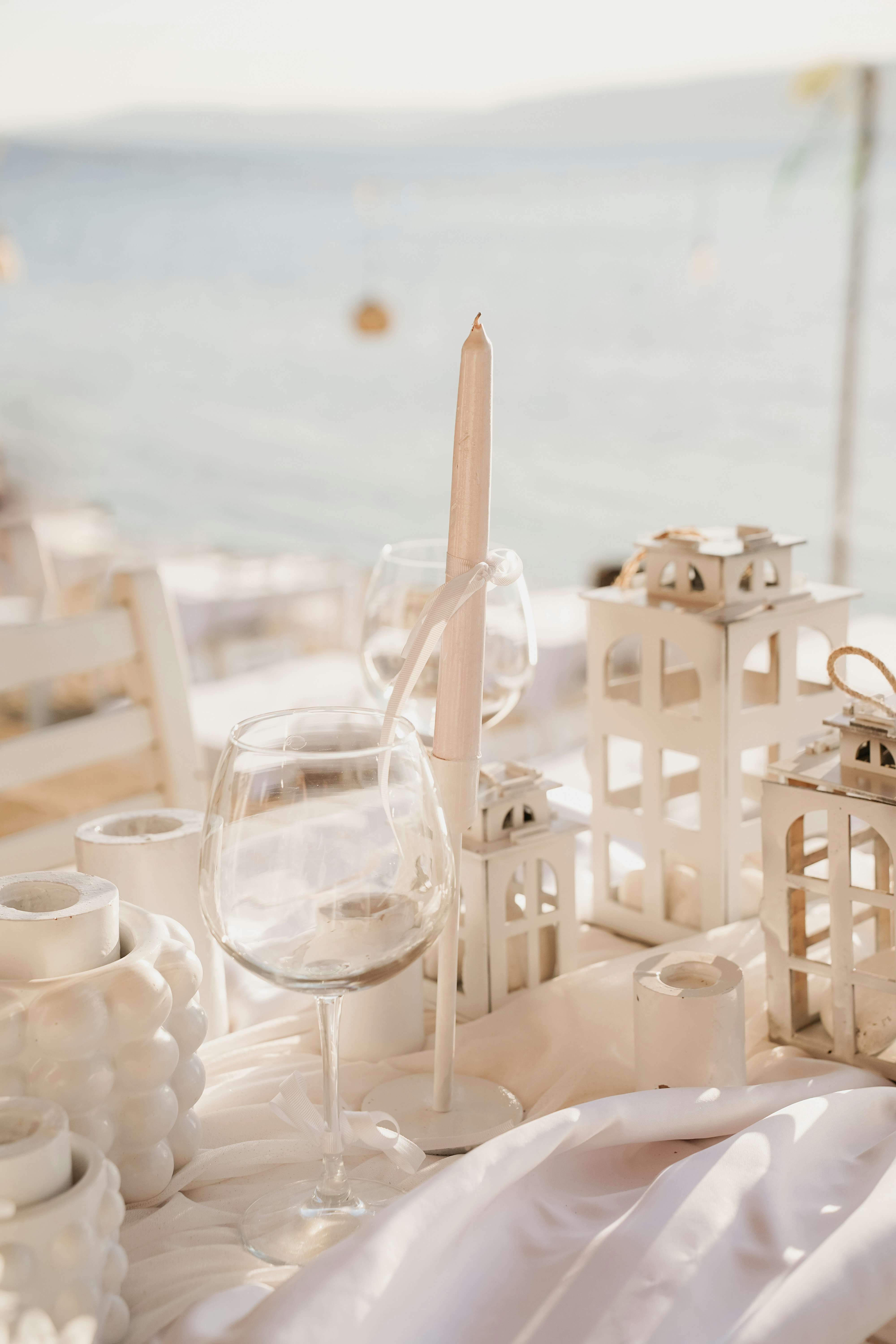 Table setting with white lanterns and candles by the sea