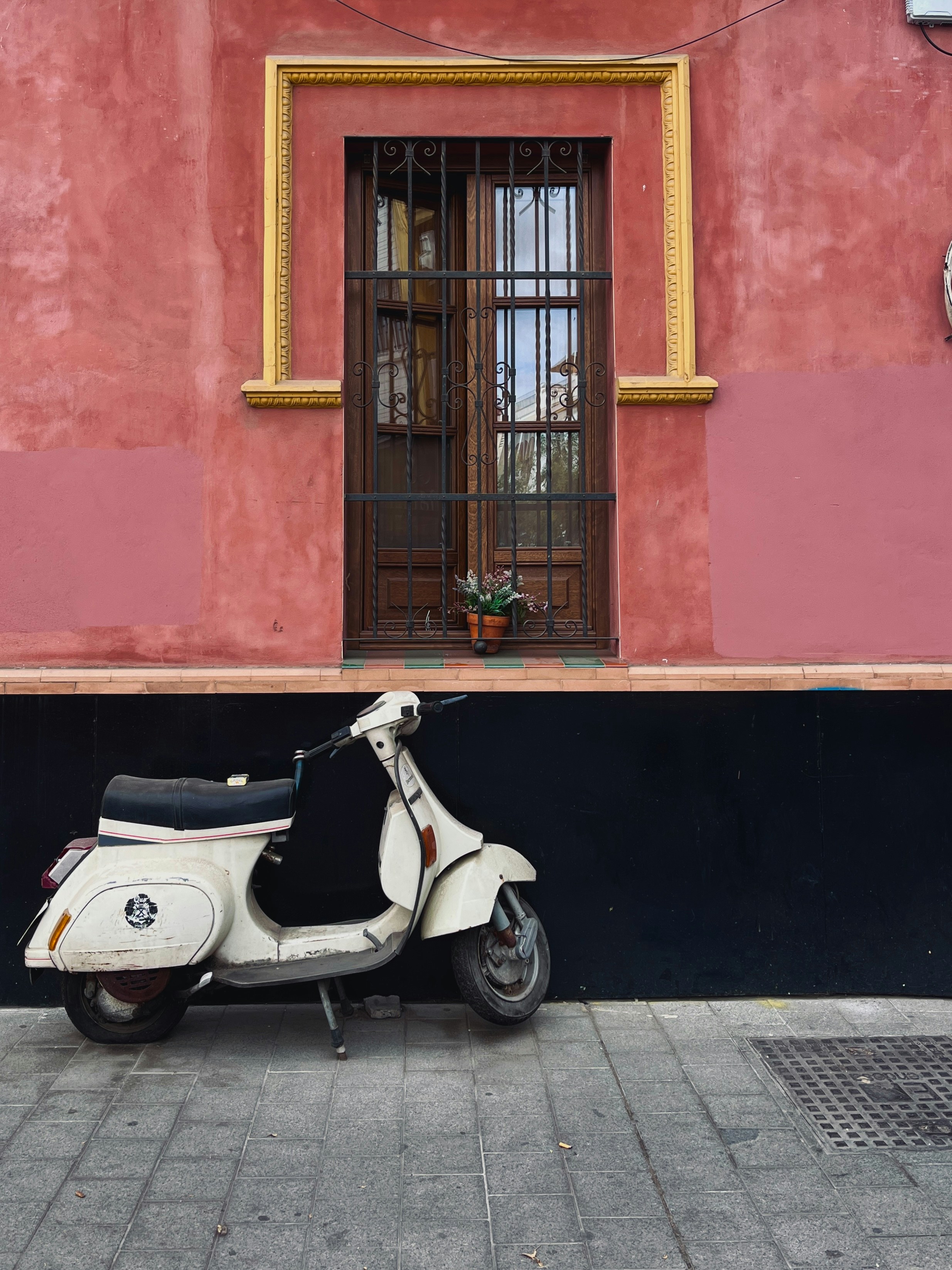 Cream colored scooter parked against pink wall