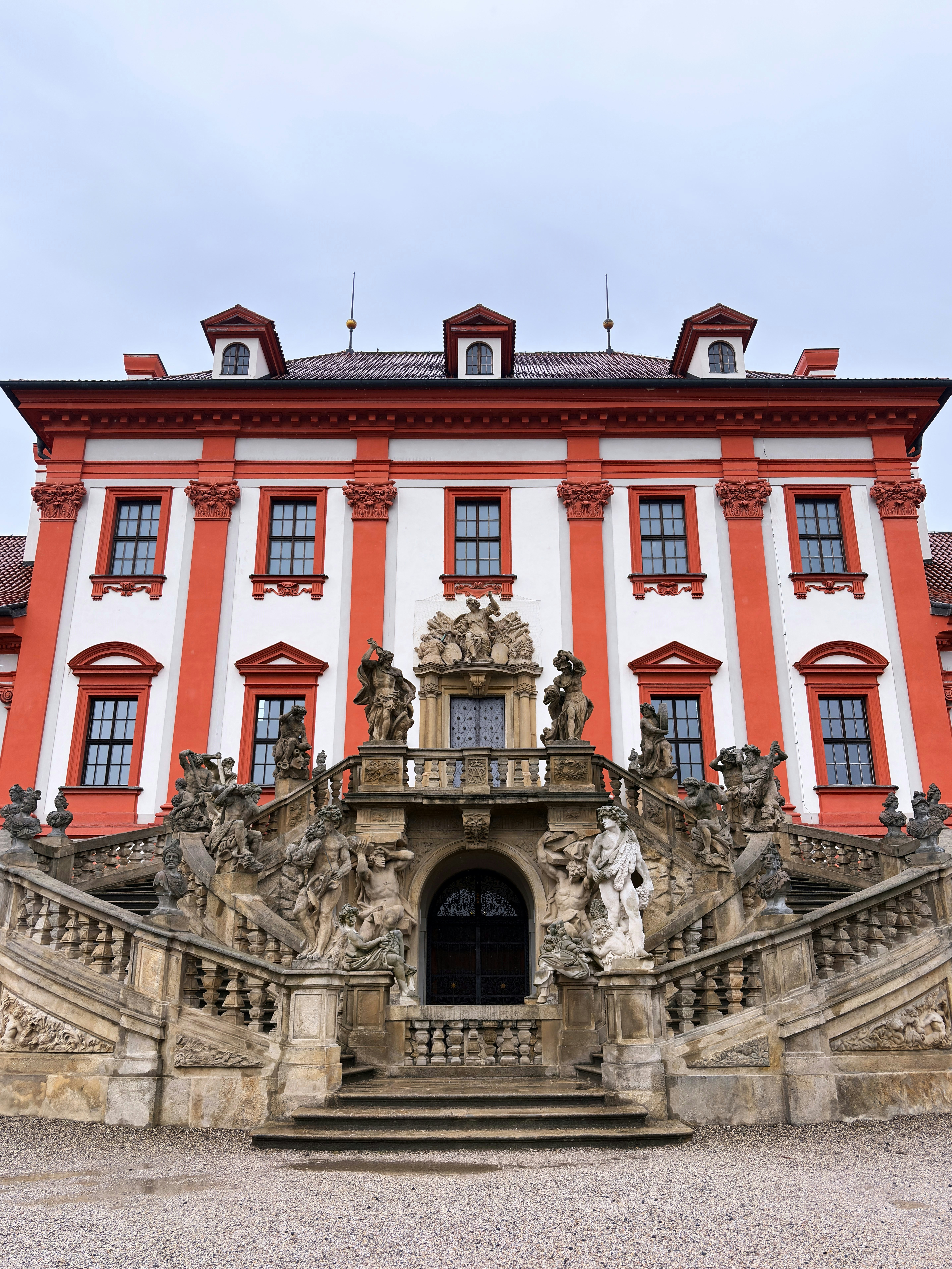 Grand ornate palace with large stone staircase and statues