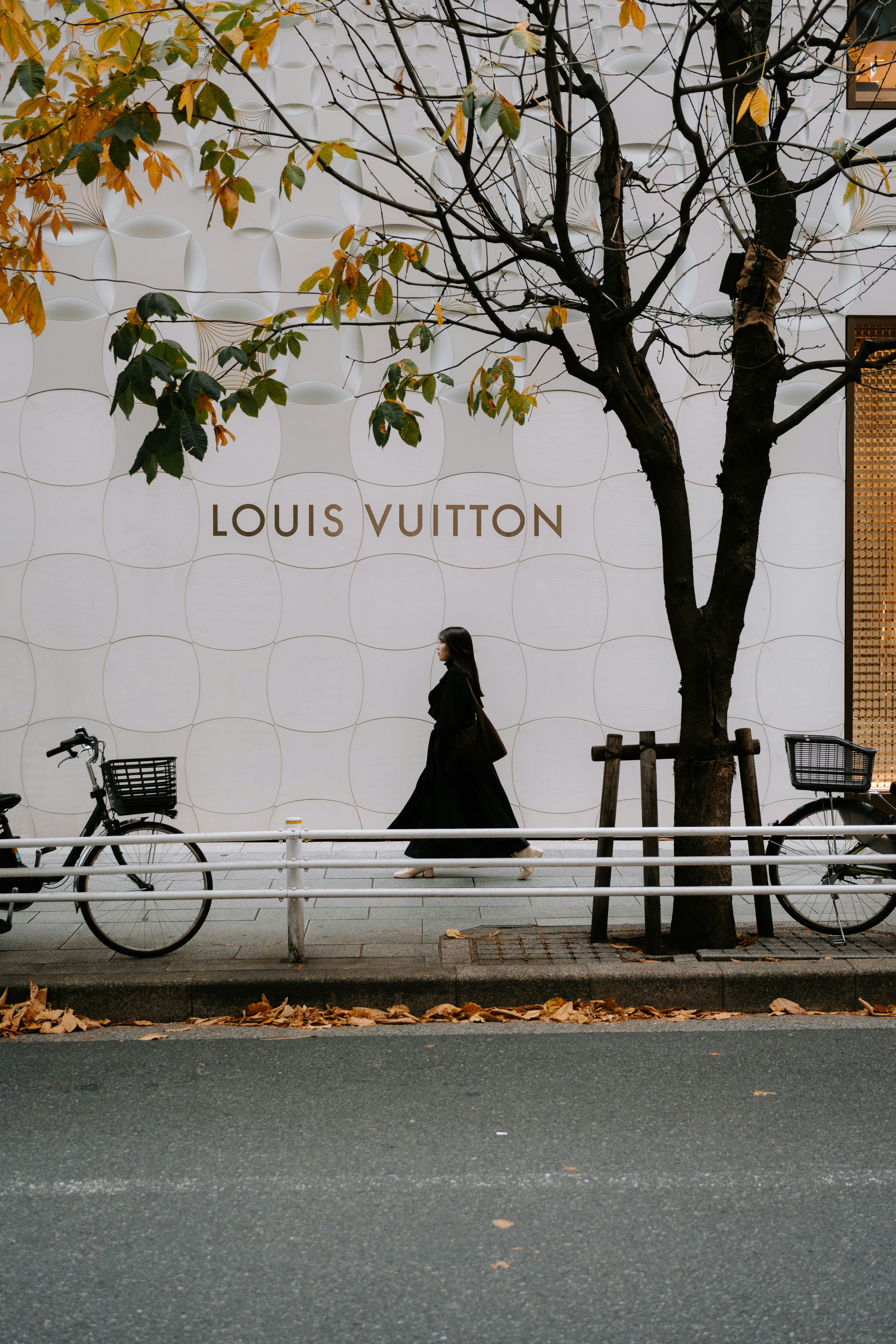 Woman walks past louis vuitton store with bicycles.