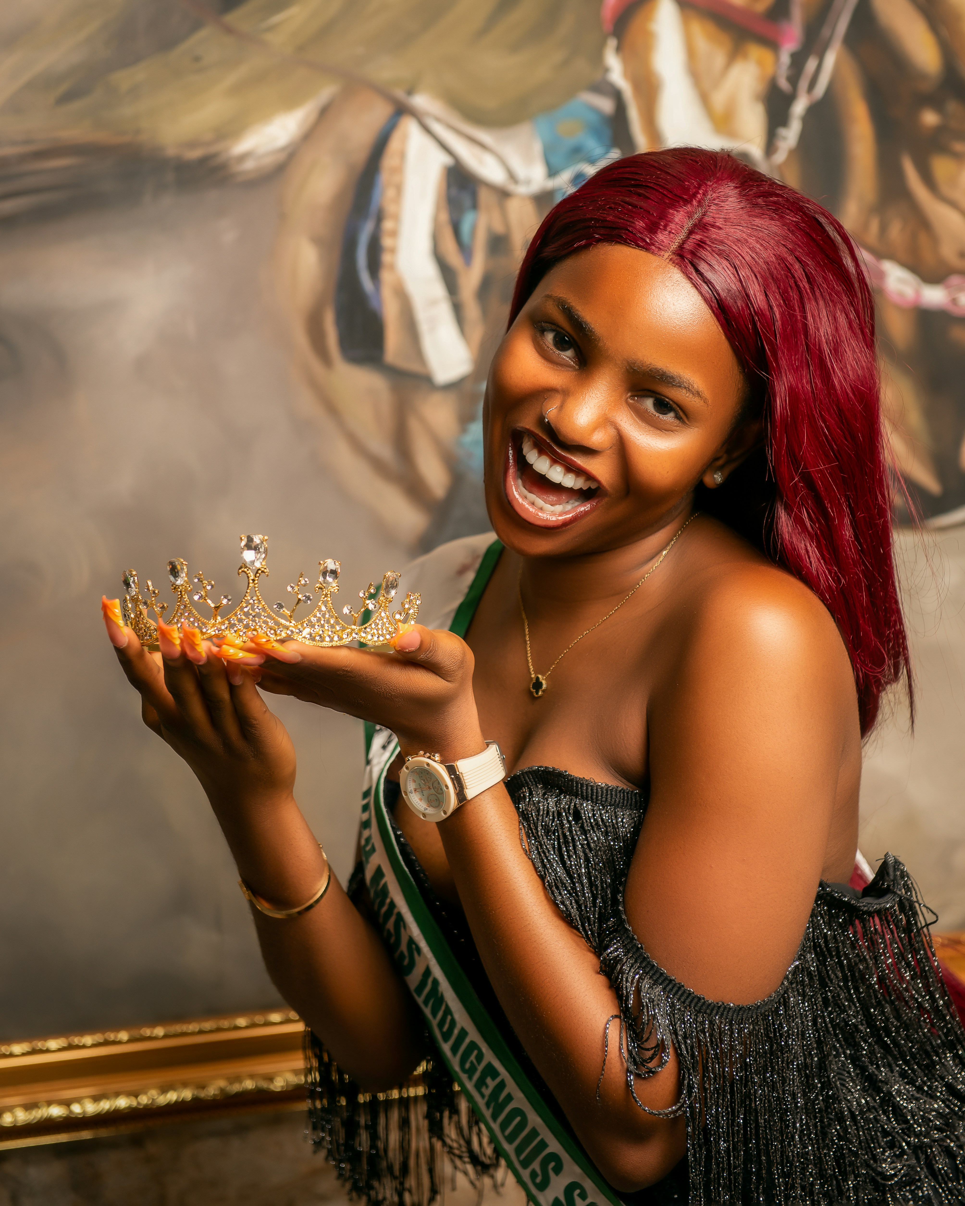 Woman in crown and sash holding a tiara