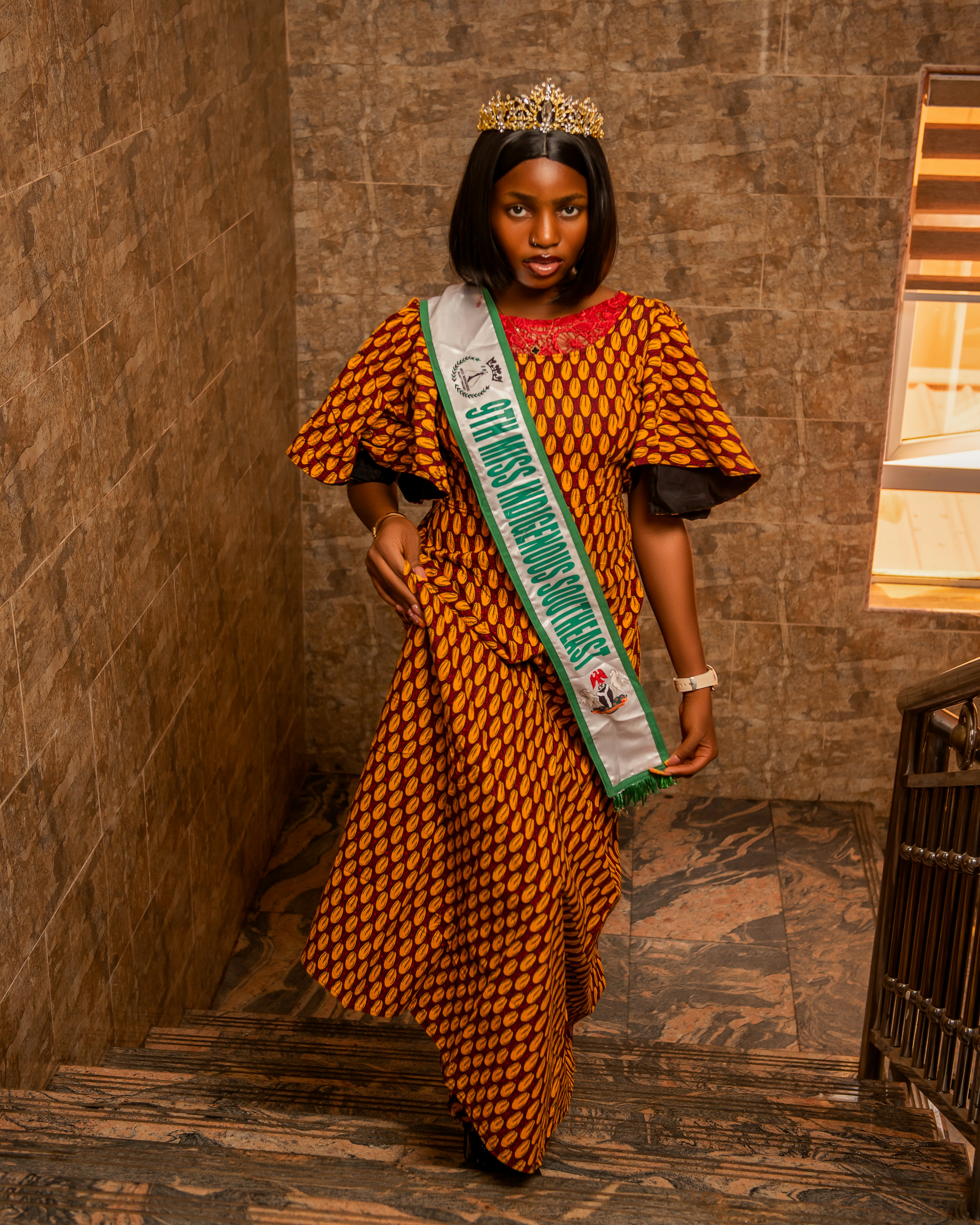 Young woman wearing a crown and sash on stairs