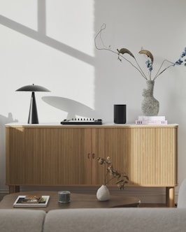 Modern wooden sideboard with decorative items and lamp.