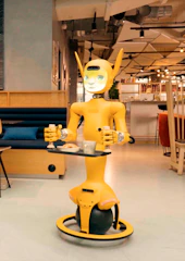 A yellow robot serving drinks and food in a cafe
