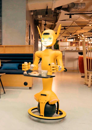 A yellow robot serving drinks and food in a cafe
