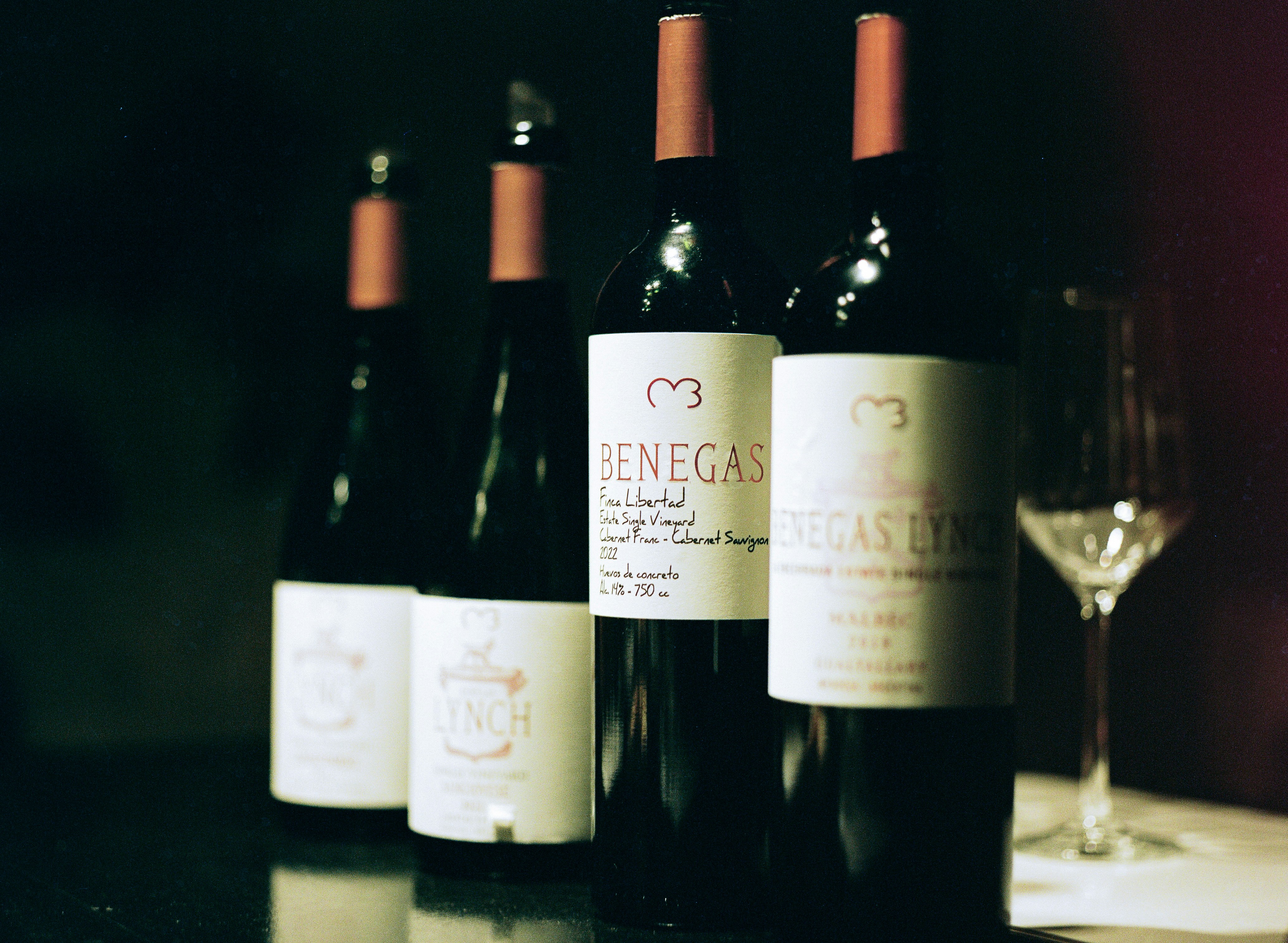 Four bottles of wine with a glass