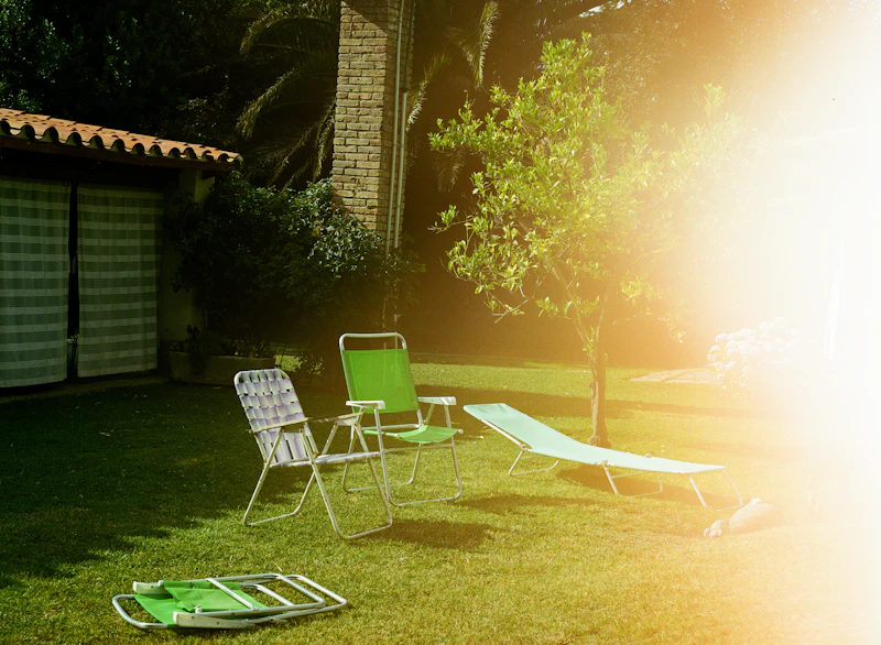 Lawn chairs on green grass next to residential home