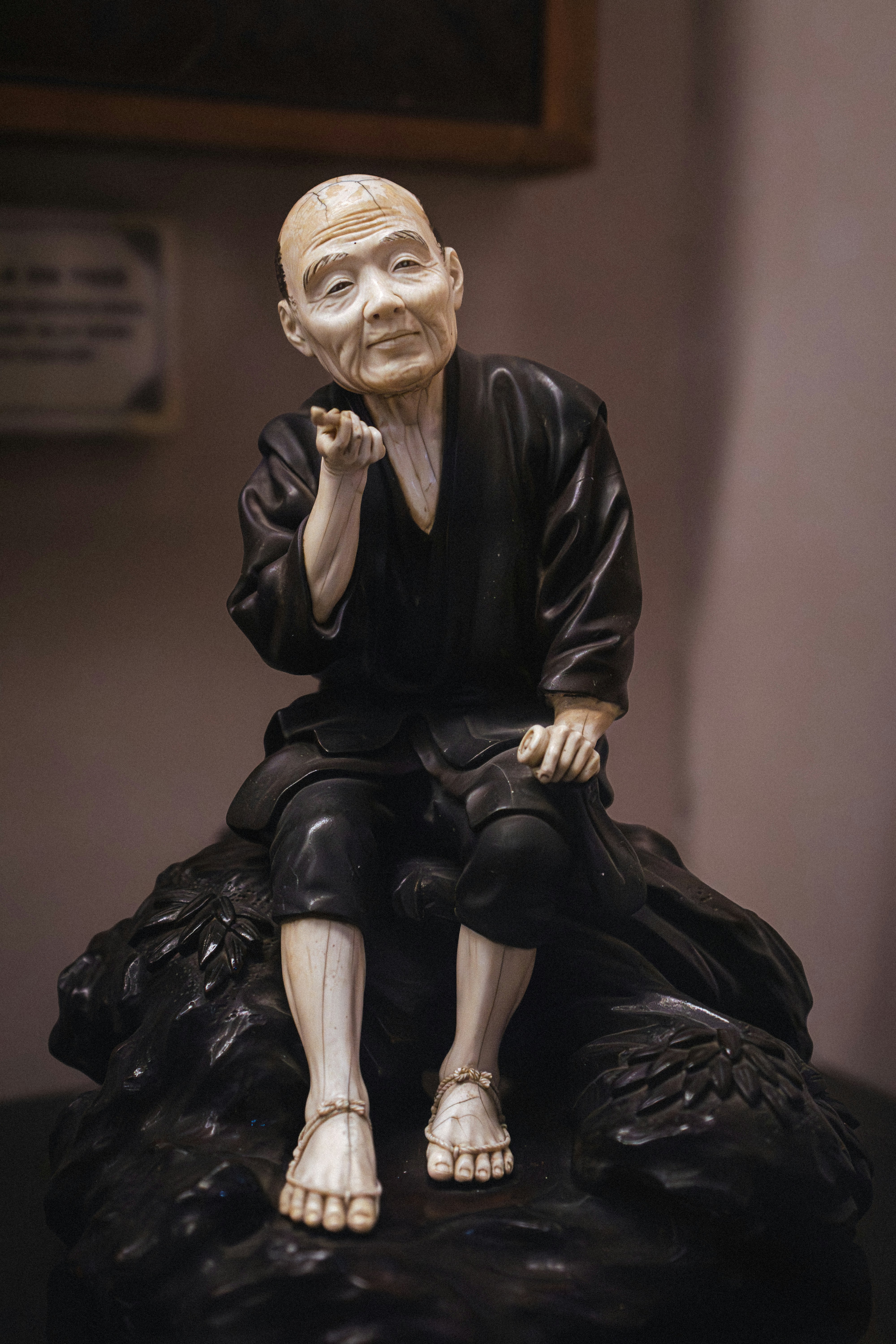 Eine alte Mannfigur steht auf einem dunklen Felsen.