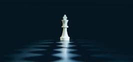 A single white chess king stands on a dark board.