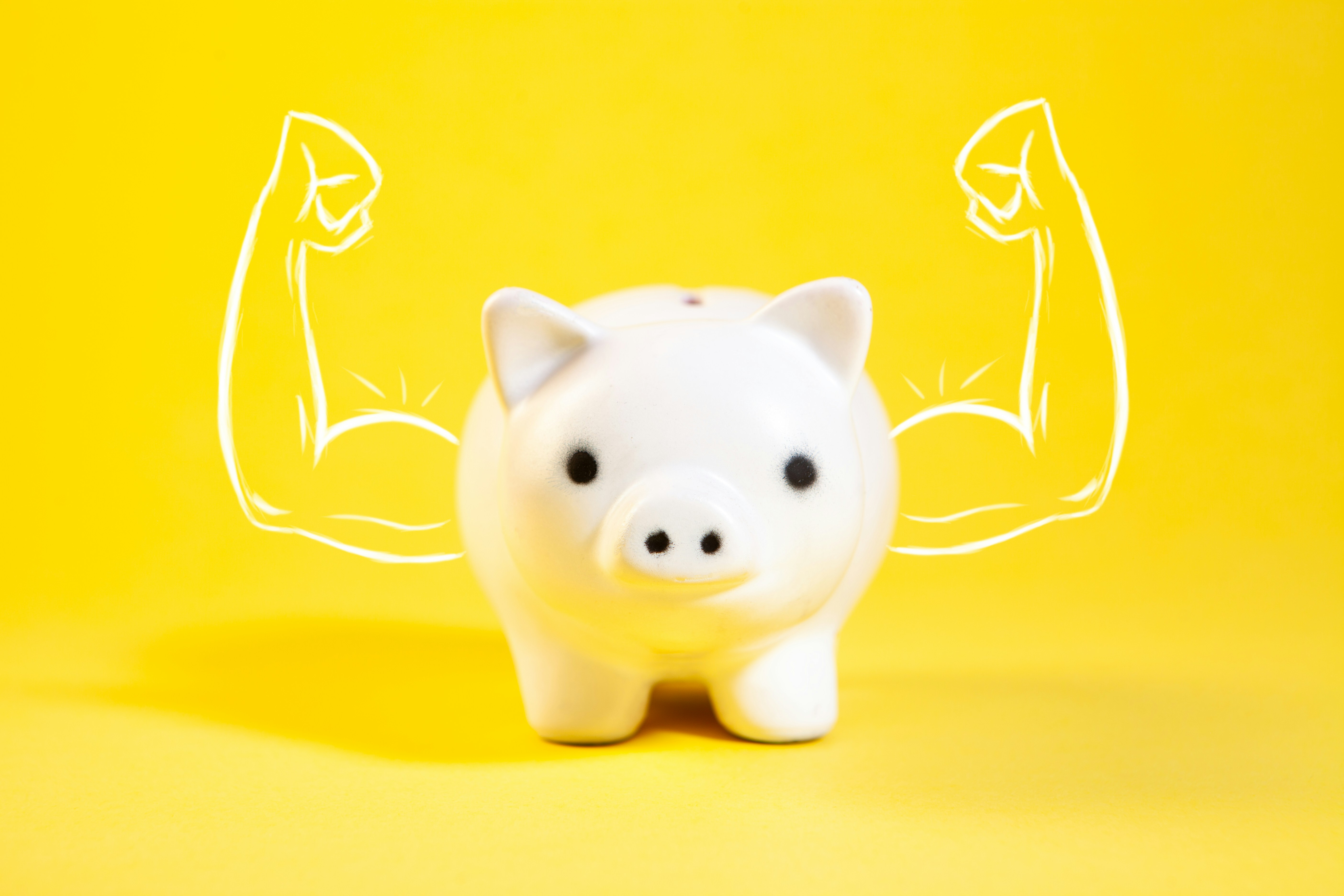 A white piggy bank with drawn muscular arms.