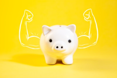 A white piggy bank with drawn muscular arms.
