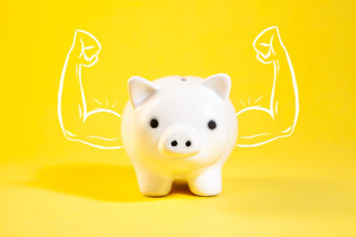 A white piggy bank with drawn muscular arms.
