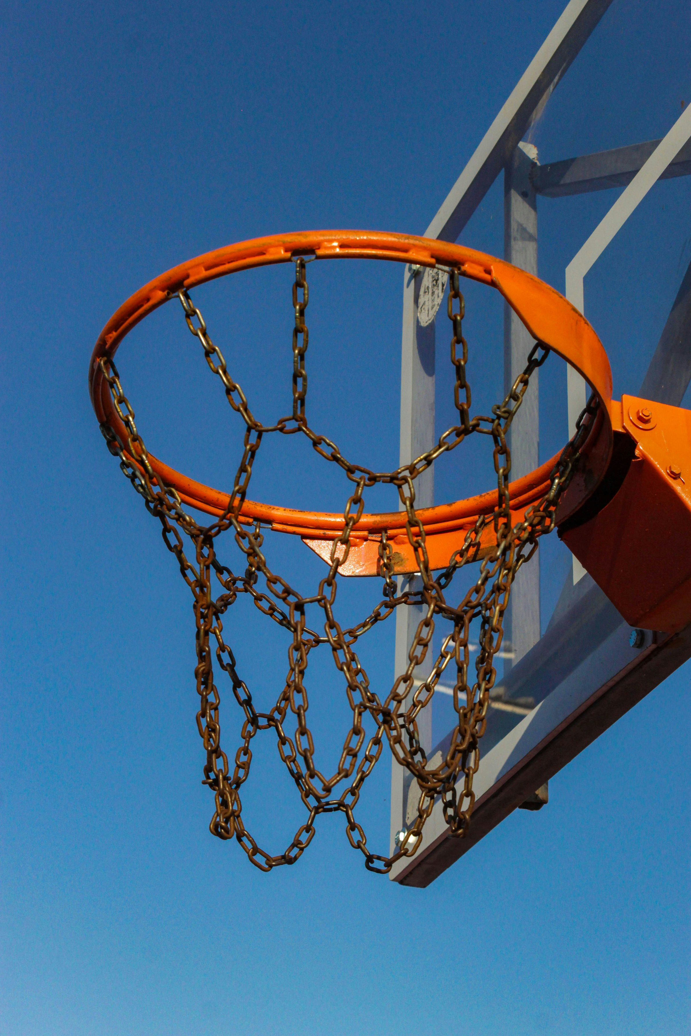 Basketball hoop with metal chain net against blue sky